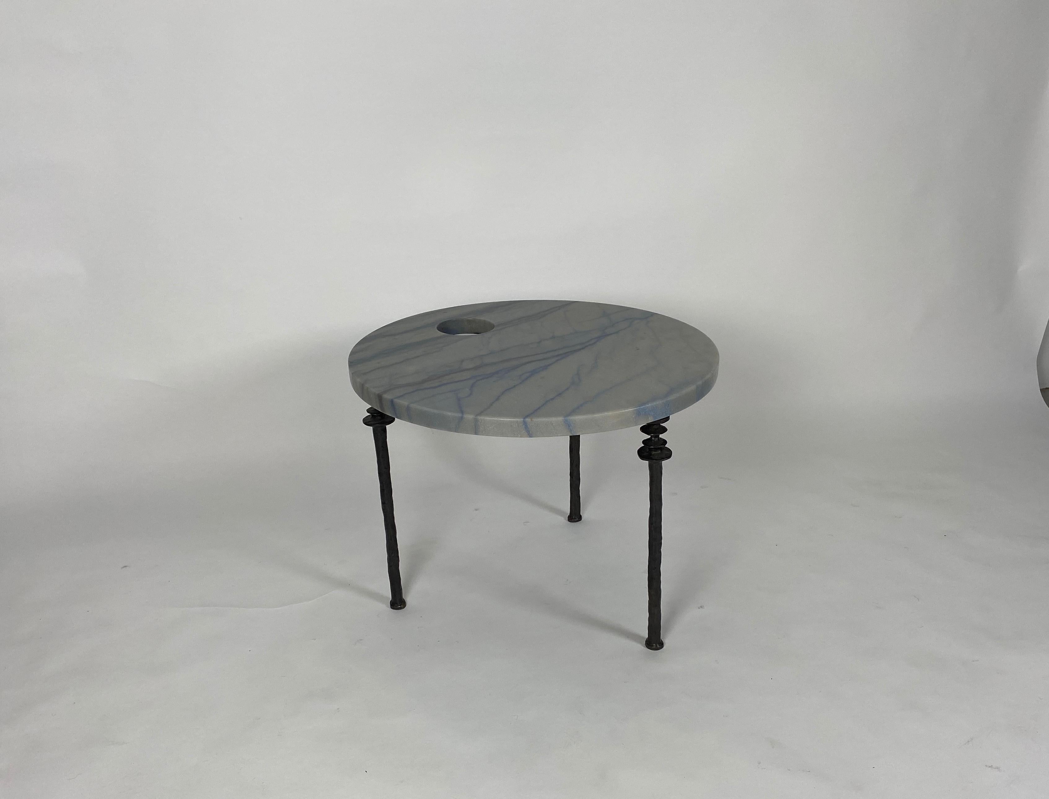 One marble-topped small scaled side tables. The round top has a single hole drilled off center in the pale blue marble top. The legs are cast silicon bronze and have a unique organic texture.
     