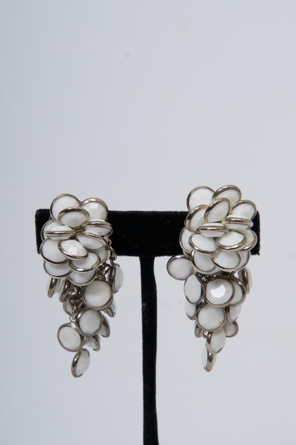 Chandelier earrings of faceted white disks encircled by silver metal cascading down from the earclip. Sorrelli (sisters) was founded in 1983 and is a female owned and operated jewelry business known for their handcrafted jewelry.