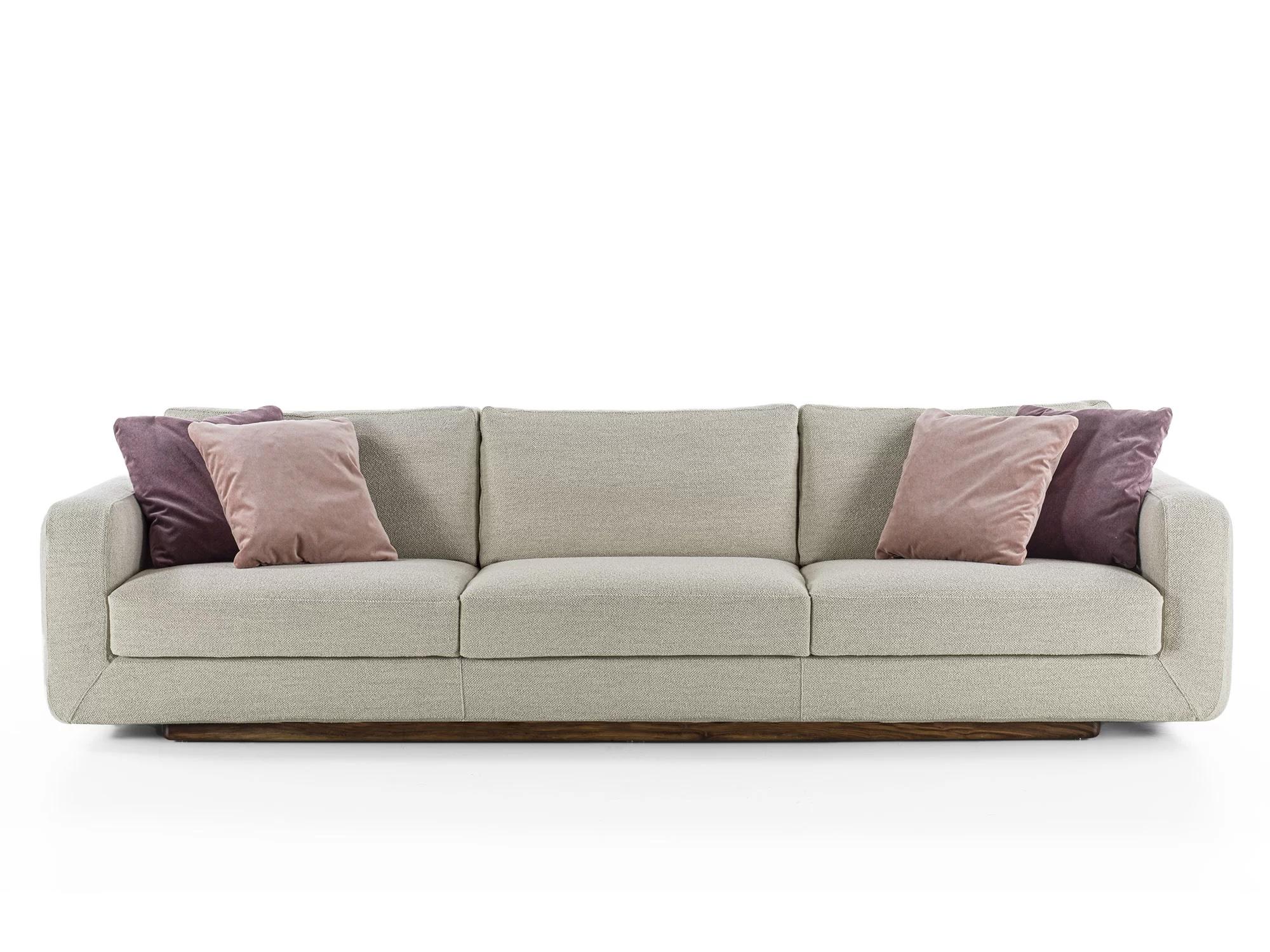 Sofa with a structure born from the union of two compenents characterized by soft, rounded lines: the solid wood base houses soft leather of fabric cushions with visible stitching.


