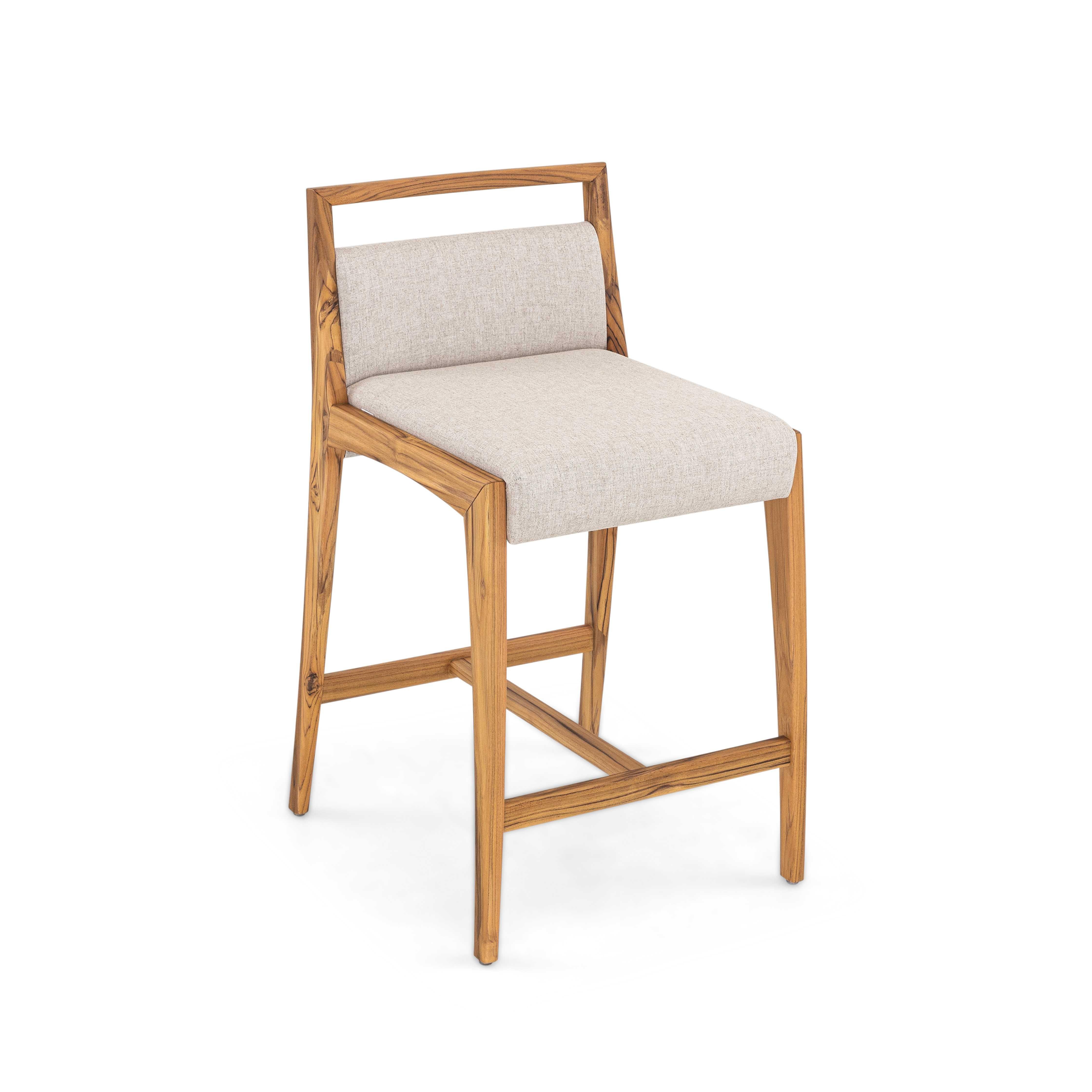 A Sotto teak wood counter stool designed by Uultis Studio with light beige fabric. The Sotto counter stool blends natural beauty with refined craftsmanship, making it a timeless addition to kitchens and dining spaces alike. Designed with a robust