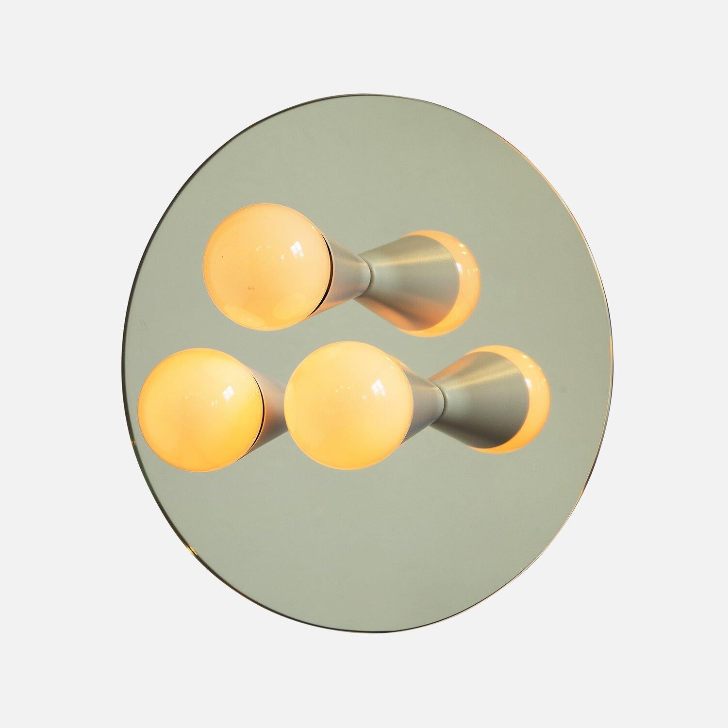 Designed by Shaun Kasperbauer for Souda

The Echo Series is a line of surface-mount fixtures that can be used on a wall or ceiling. White or brass cones mount to mirrored glass to perfectly reflect each bulb, giving the illusion of lights floating