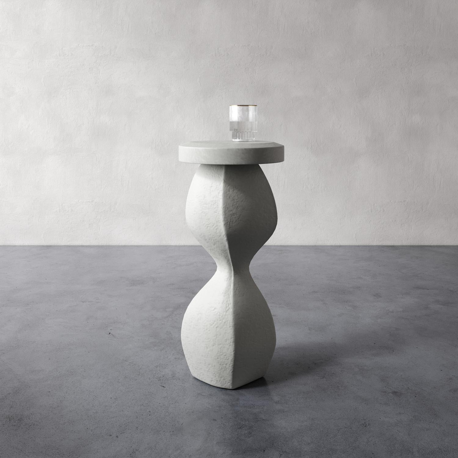 La table à boire Souple est une petite pièce sculpturale en plâtre à la forme organique et ondulante. D'une hauteur idéale pour accueillir des boissons ou un livre, il allie fonctionnalité et design artistique. Sa taille compacte le rend parfait