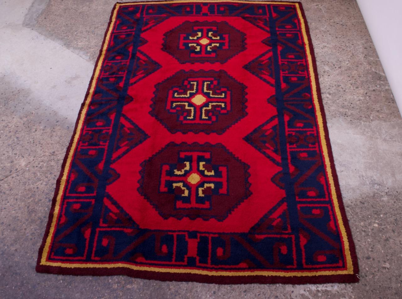 South Asian (likely Pakistani) machine-made rug boasting vibrant colors of red, yellow, and blue, circa 1980s. Inspired by Baluch / Afgani carpets, the pattern is rich with geometric motifs. Design is reminiscent of a symbol developed by interior