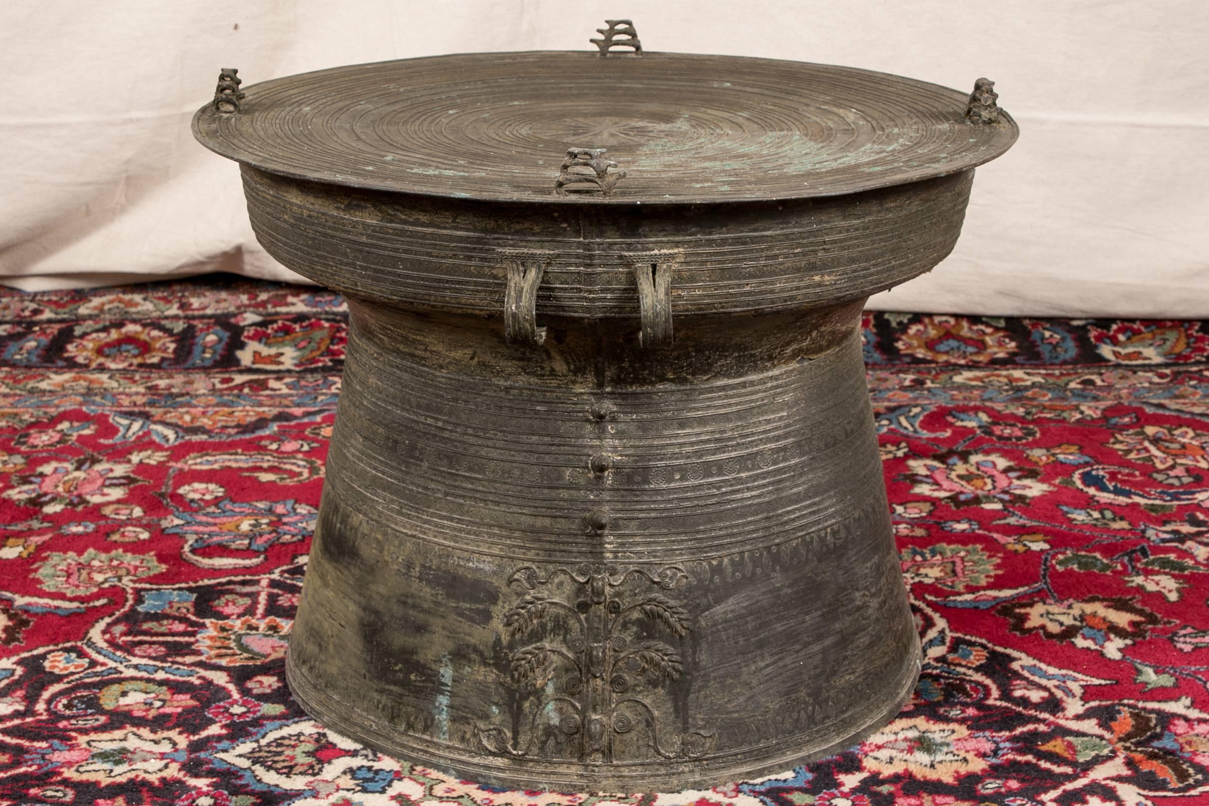 South Asian bronze rain drum table, circular with concentric circles on the top and curved sides decorated with geometric motifs, top with four pierced stylized animal motifs in tiers and a star in the centre. Loop handles on the sides, one side