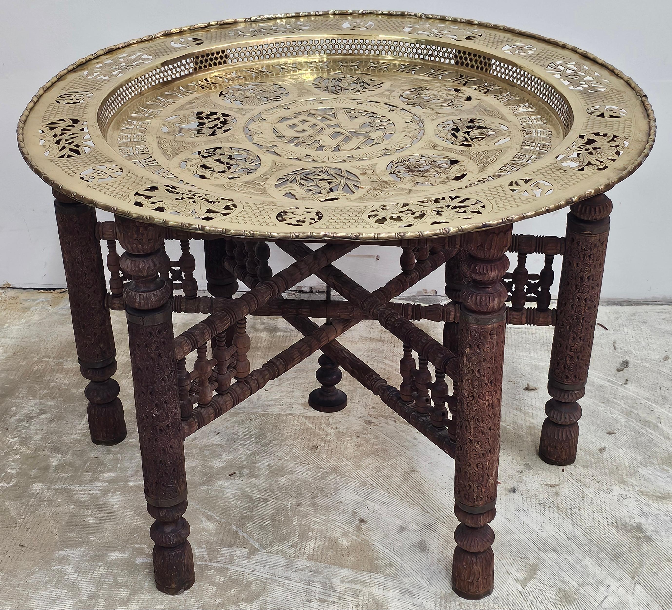 Foldes en bois et bois sculpté d'Asie du Sud-Est du début du 20e siècle  Table de cocktail à plateau en laiton percé avec 8 scènes figuratives percées en laiton autour d'un plateau central calligraphié. Le plateau supérieur repose sur six pieds