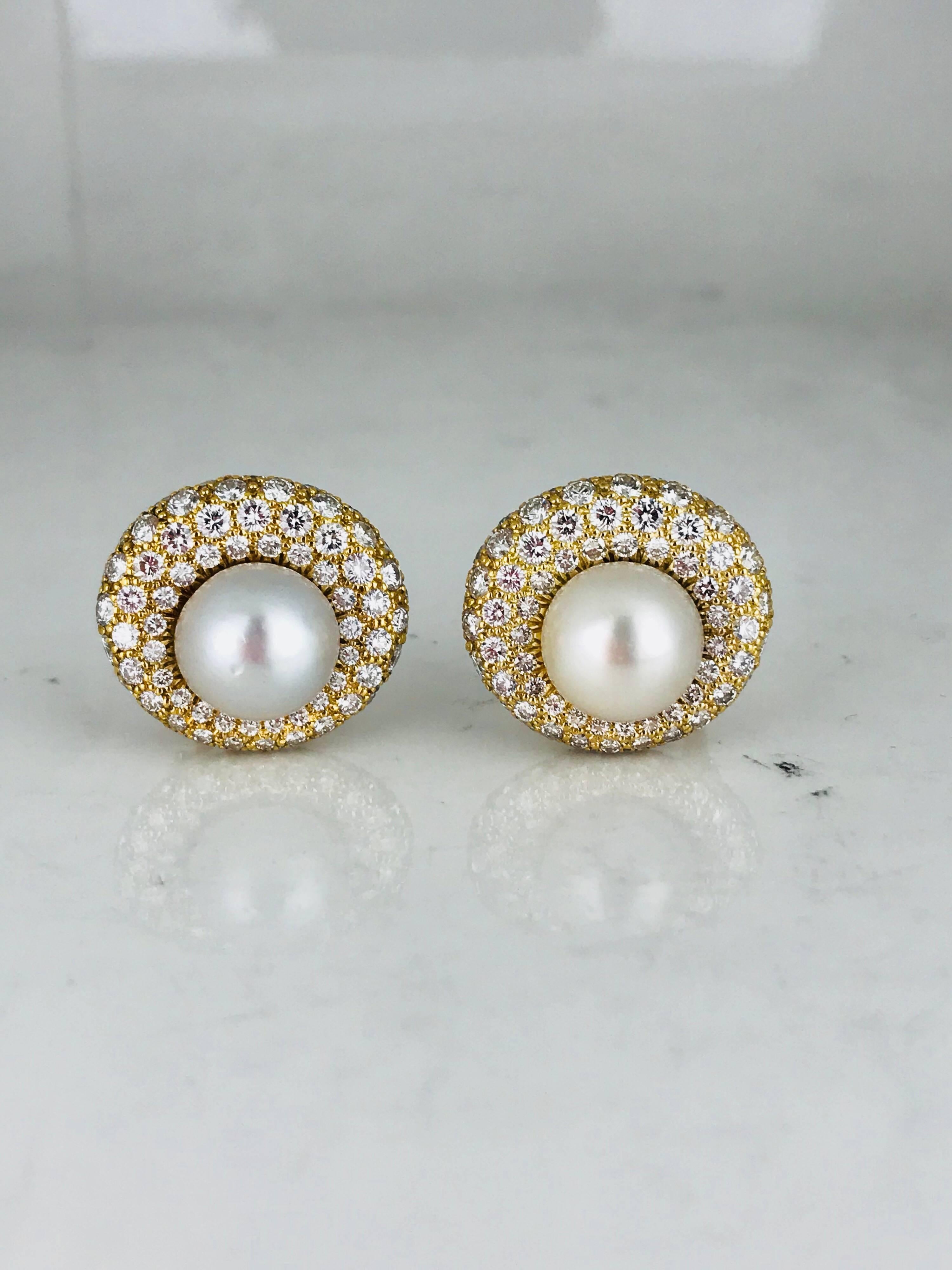 Stunning, 11-11.25  millimeter Pearls surrounded with diamond in a  pave setting. These Reto and timeless earrings feature a fine, high lustered 11-1.25 millimeter center South Sea pearl. 
The  setting is curved as the diamonds are set to wrap down