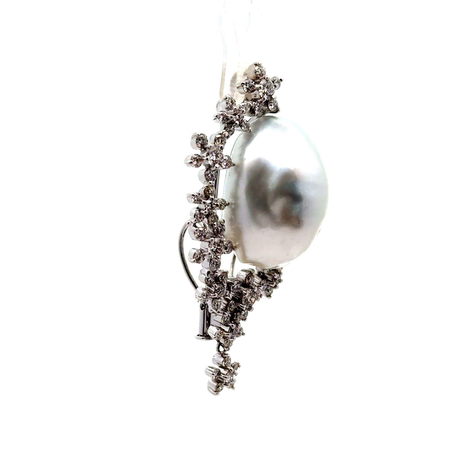 A striking brooch featuring a lustrous south sea pearl as its centerpiece measuring an impressive 30mm in length! It has a strong luster that makes light roll across its surface and shine brightly. Surrounding the pearl, a delicate arrangement of