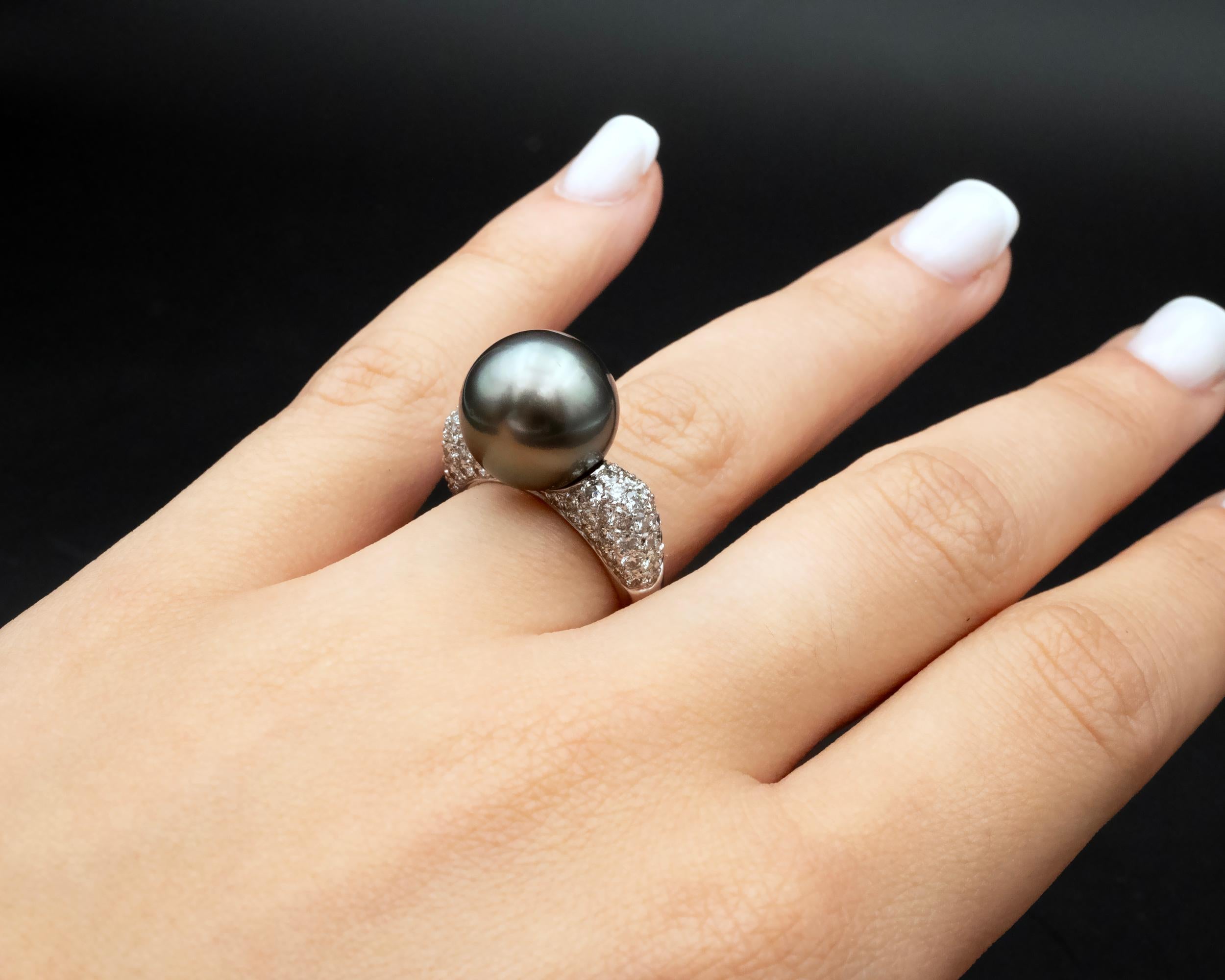 Elegance meets modern sophistication in this 18 karat gold ring, featuring a stunning 13 millimetre south sea Tahitian pearl weighing 16.54 carats with captivating dark grey hues and subtle pink and green overtones. 
The shank is pavé set with 1.61