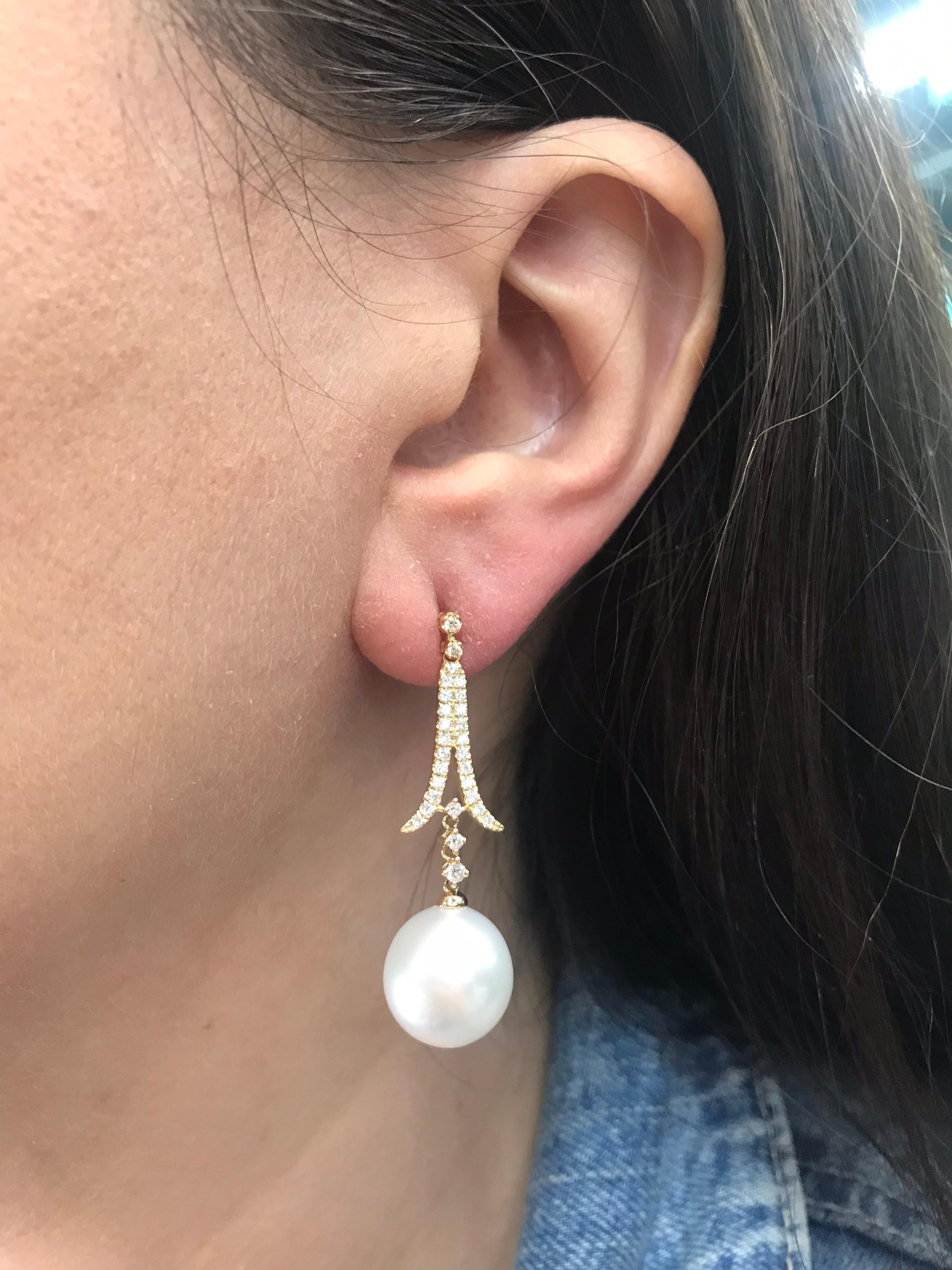 18K Yellow gold drop earrings featuring 56 round brilliants weighing 0.60 carats and two South Sea pearls measuring 12-13 mm. 