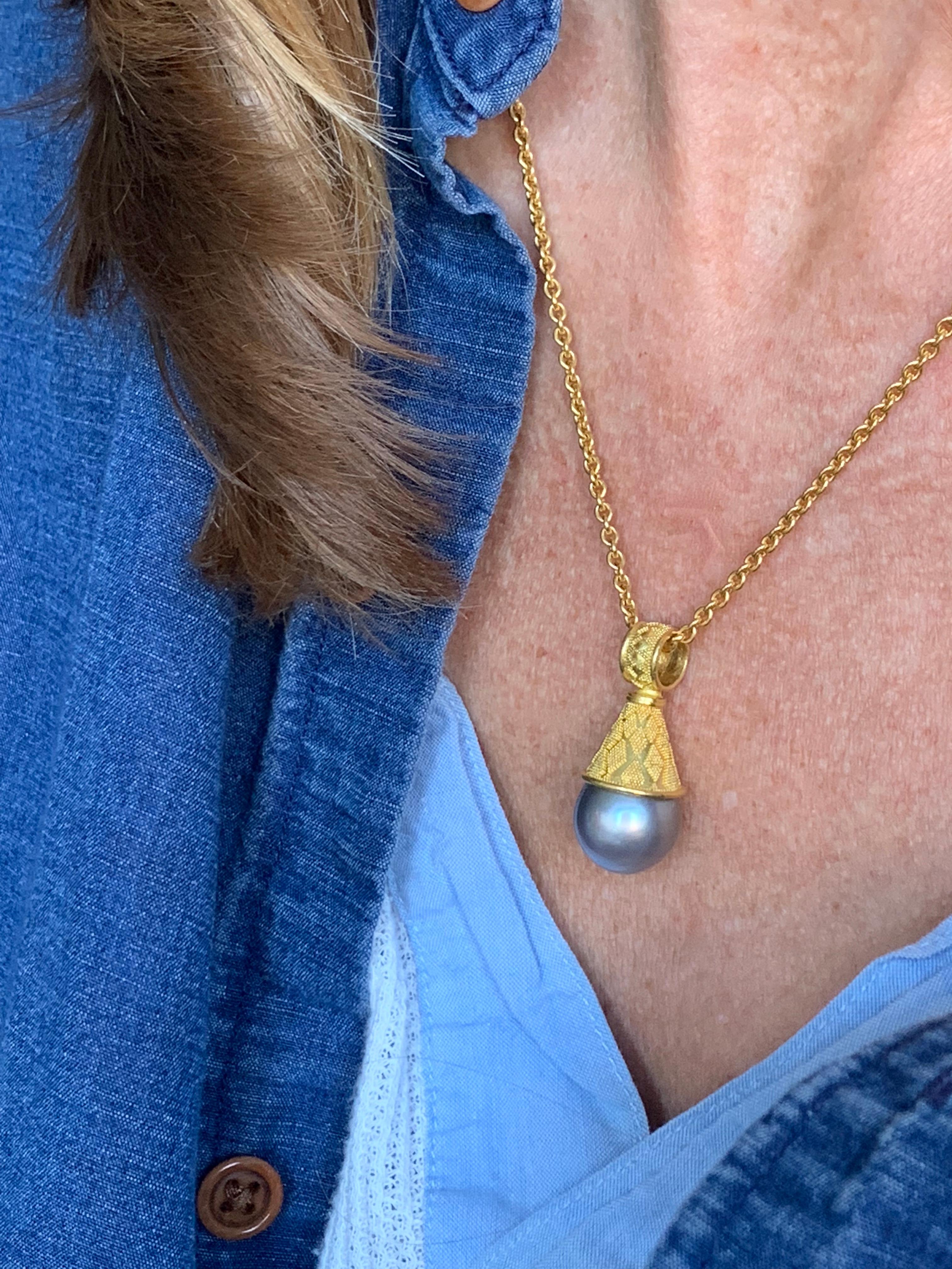 In the manner of Etruscan jewelry, this Tahitian grey pearl pendant is meticulously ornamented with delicate granulation in 22 karat gold and set in a cone cap and bail. Appearing both soft and metallic, grey pearls are the perfect blend of modern