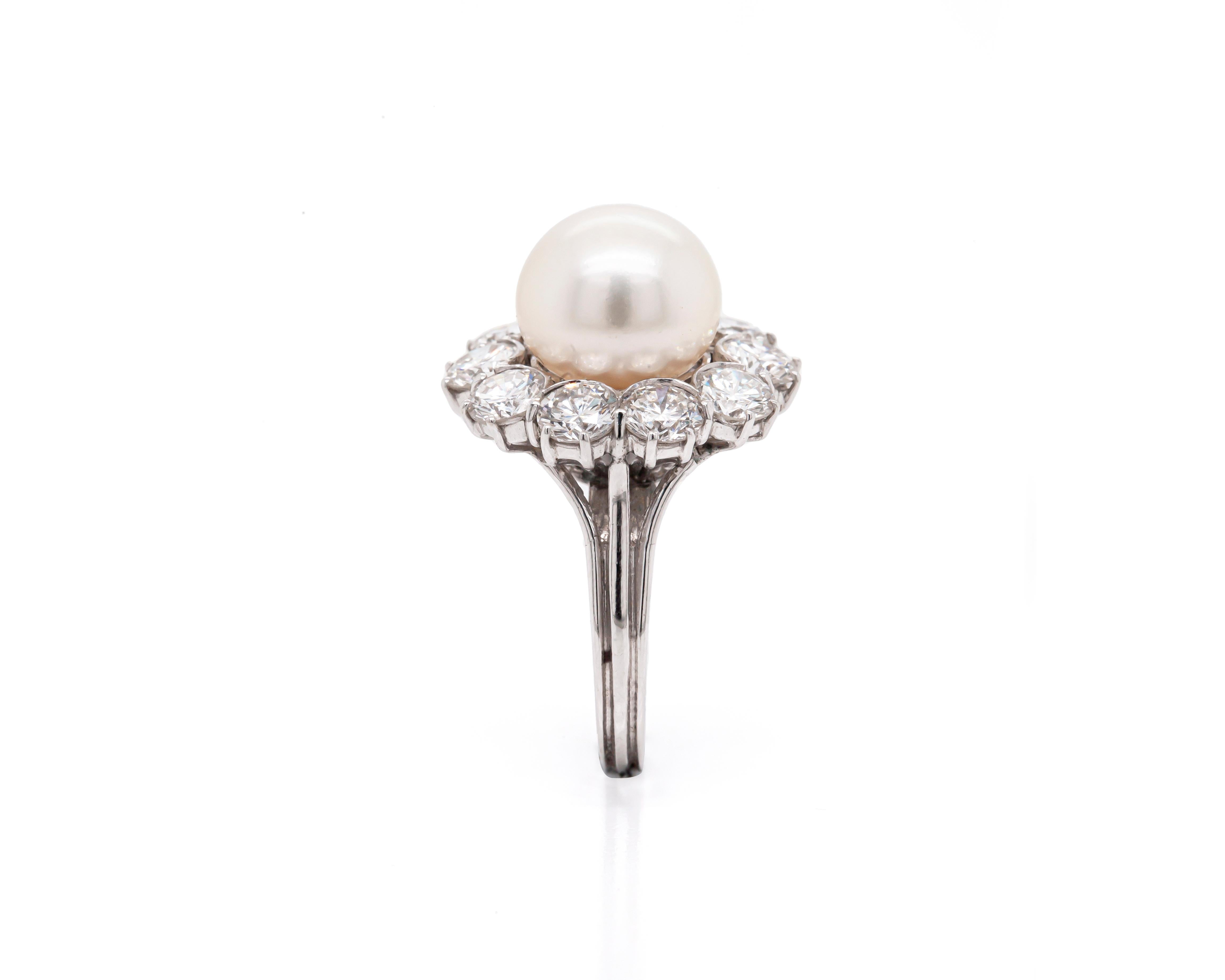 This charming cluster engagement ring, exquisitely crafted from 18 carat white gold, is centred with a beautiful South Sea pearl measuring 10.35mm. Surrounding the delicate pearl and accenting its lovely lustre there are 10 fine quality round