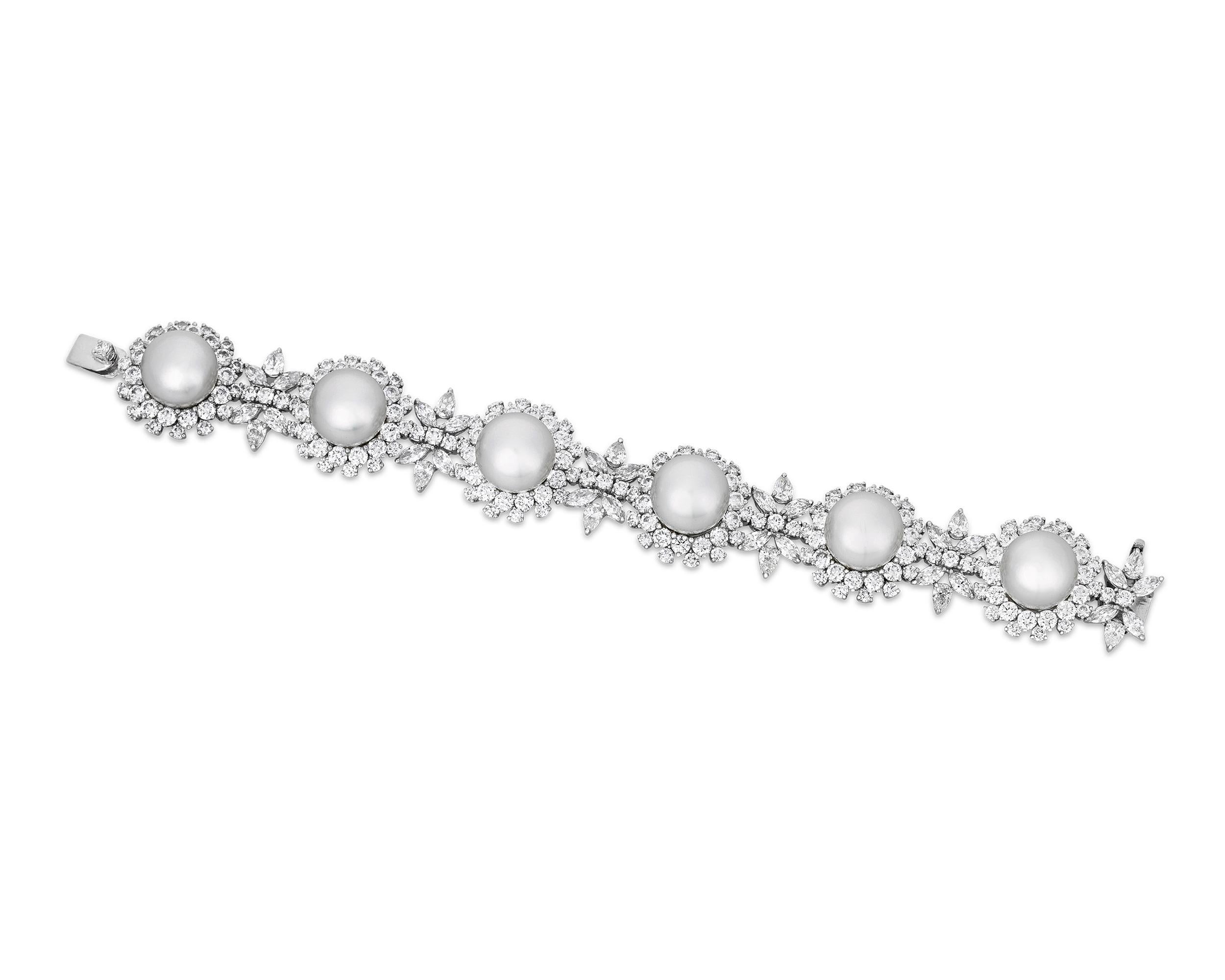 Six South Sea pearls measuring 13.5mm comprise this elegant bracelet, and the gems exhibit the perfect hue and luster for which pearls from the South Sea are renowned. Florets of sparkling diamonds totaling 24.10 carats surround the pearls, adding