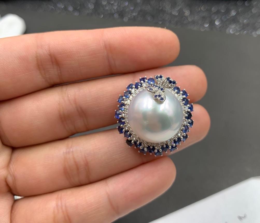 The design is inspired by butterfly resting on top of a flower. The massive 17mm White Australian South Sea Pearl is surrounded by vivid blue sapphire pave. On top the the pearl is a butterfly encrusted in vivid blue sapphire and diamonds. We also