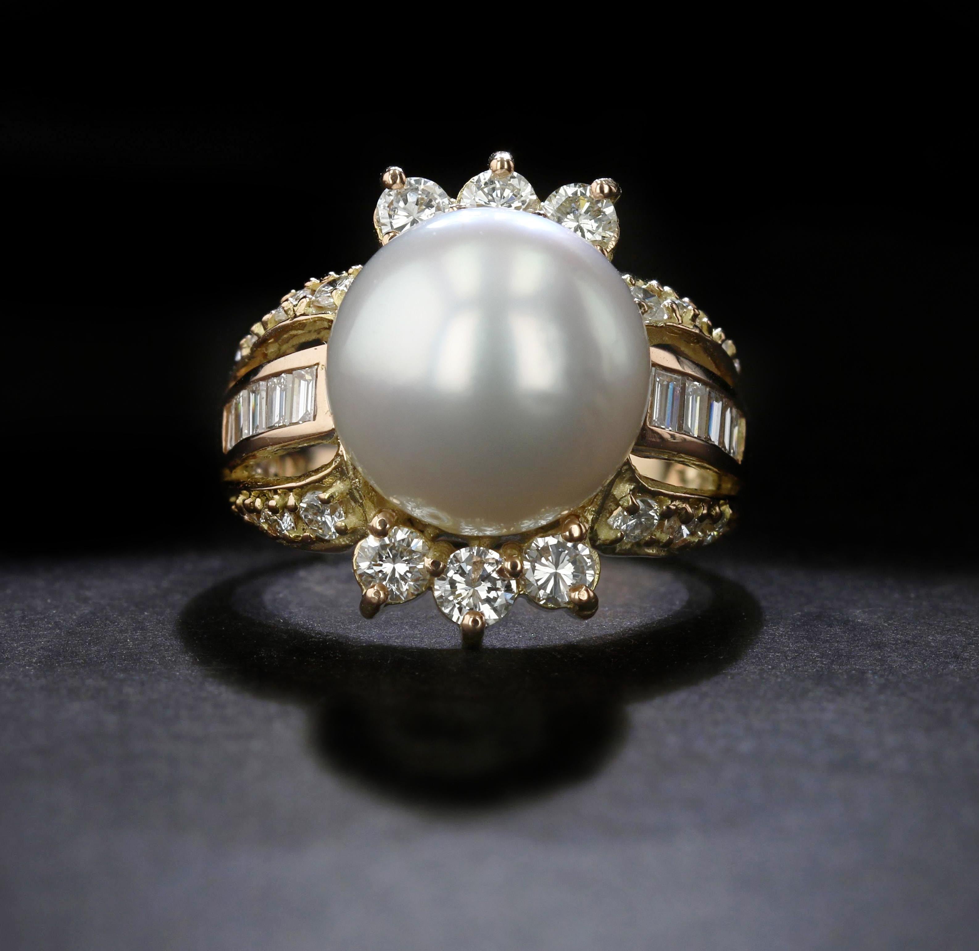 This estate ring is centered by a round, white South Sea pearl of approximately 12.50 millimeters. The ring is crafted in 14k yellow and rose gold and features a geometric split shank set with round and baguette diamonds. A trio of round diamonds