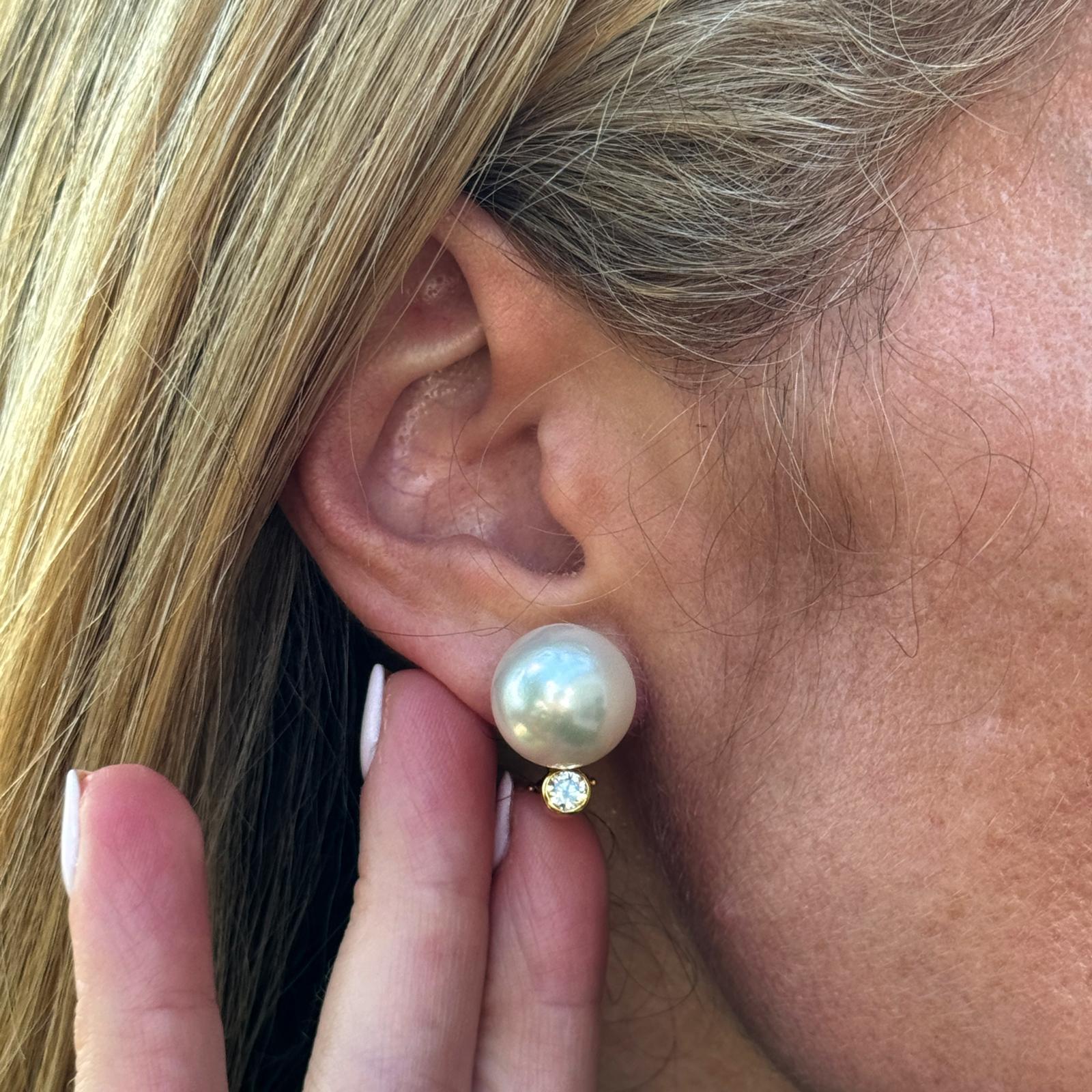 The South Sea Pearl Diamond Earrings  are a stunning display of luxury and elegance. Featuring lustrous 13.7mm South Sea pearls, these earrings are accented with 2 sparkling round brilliant bezel-set diamonds, all set in rich 18 karat yellow gold.