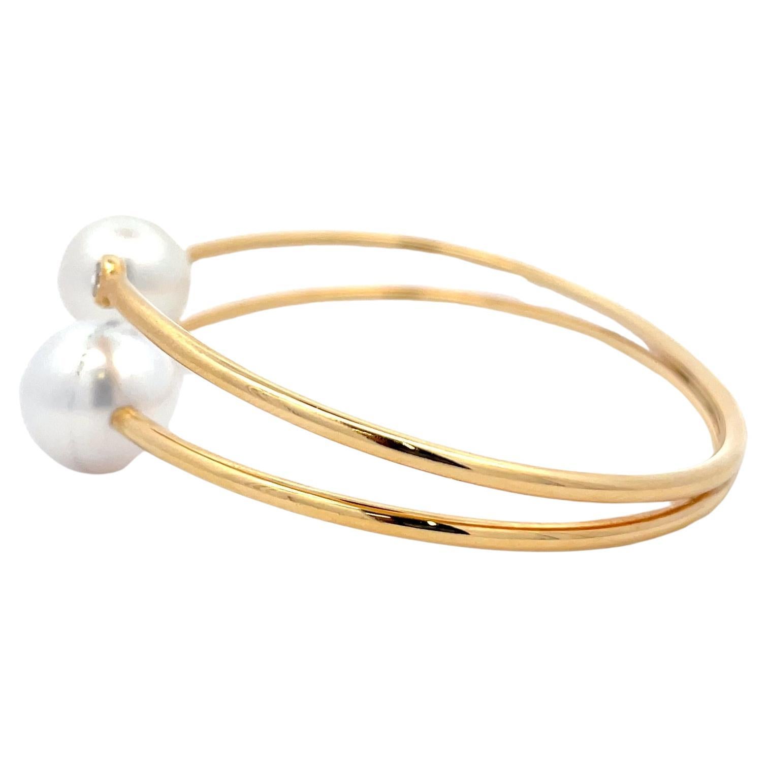 18 Karat yellow gold bangle cuff with 2 diamonds weighing 0.12 Carats and 2 South Sea Pearls measuring 9.50-10 mm. 