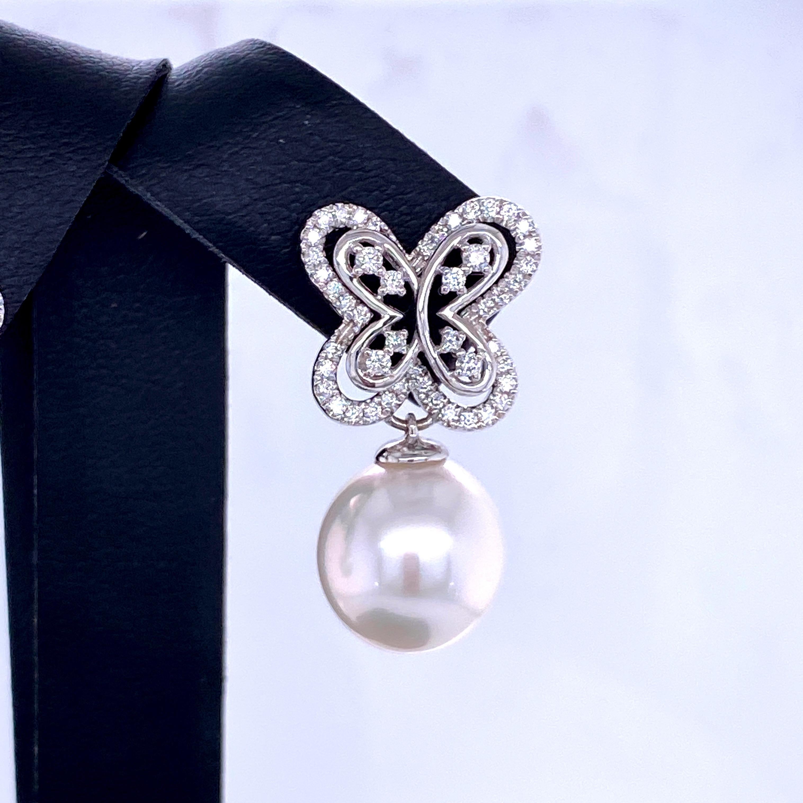 18K White gold drop earrings featuring two South Sea Pearls measuring 11-12 mm with a diamond butterfly motif containing 96 round brilliants weighing 0.54 carats.
Color G-H
Clarity SI