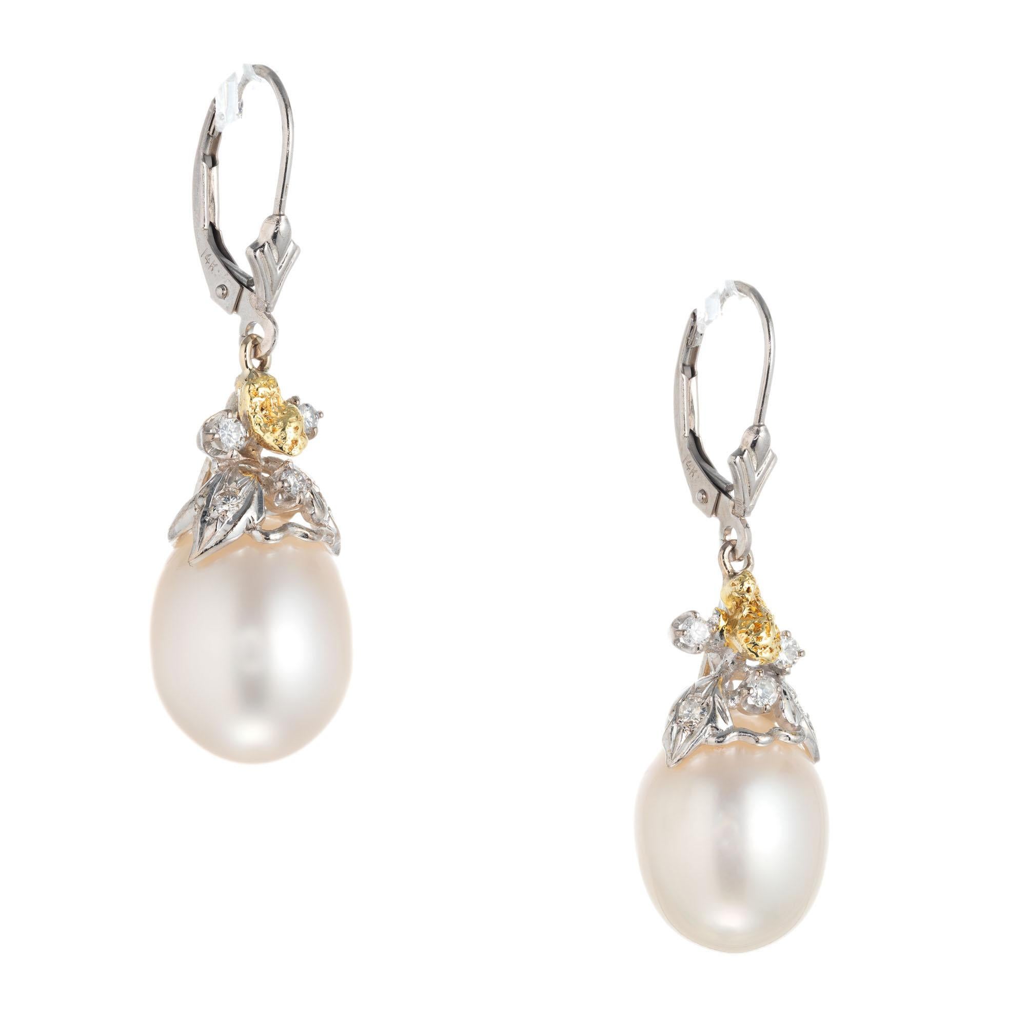 Pearl and diamond dangle earrings.  2 south sea oval pearls set in 14k yellow and white gold with round accent diamonds. Lever backs. 

2 south sea pearls. 15mmx11.7mm
10 round diamonds approx. total weight: .20cts  H, VS-SI
Length: 38.71mm or 1.52