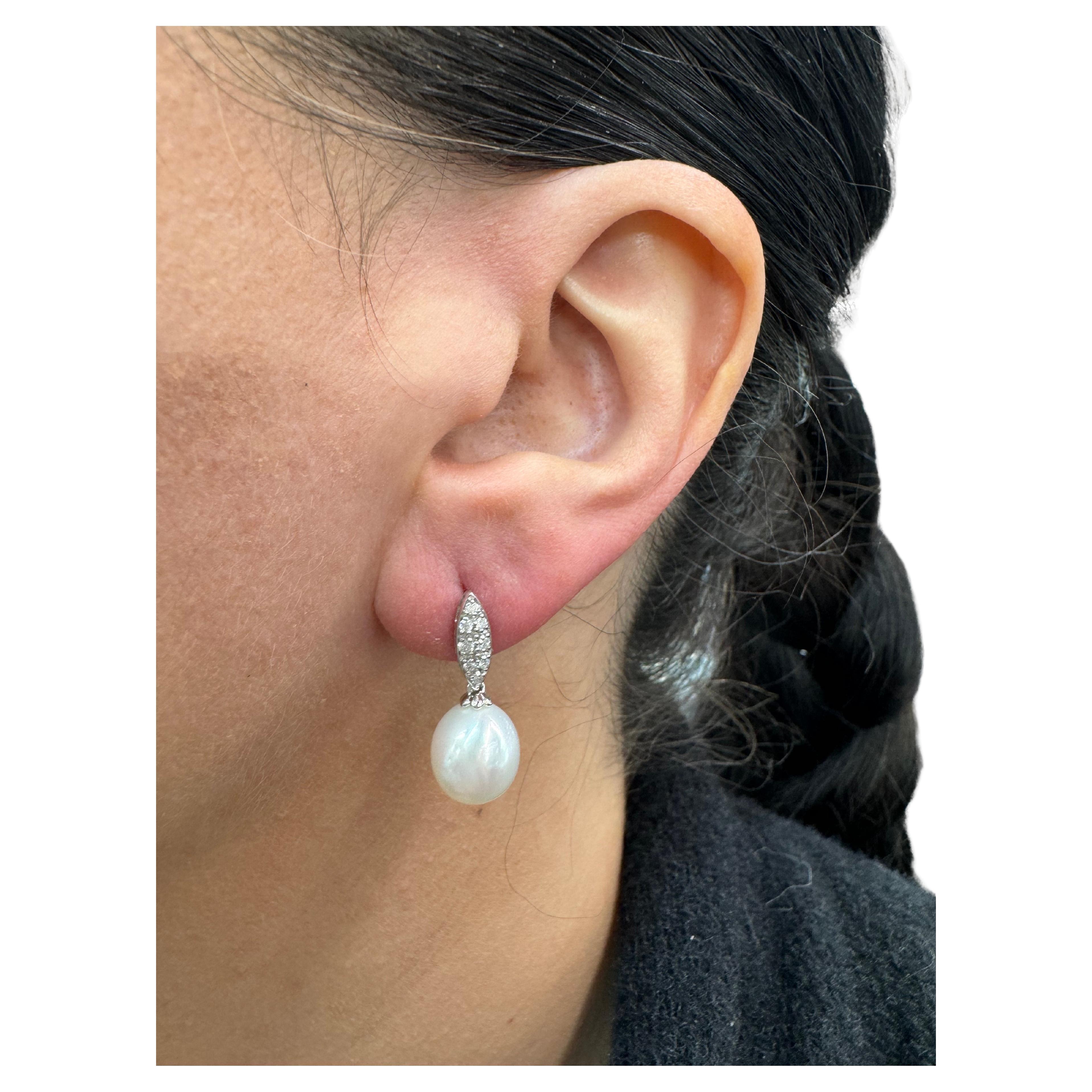 18 Karat white gold drop earrings featuring 16 round brilliants weighing 0.22 carats and two South Sea Pearls measuring 9-10 mm. 