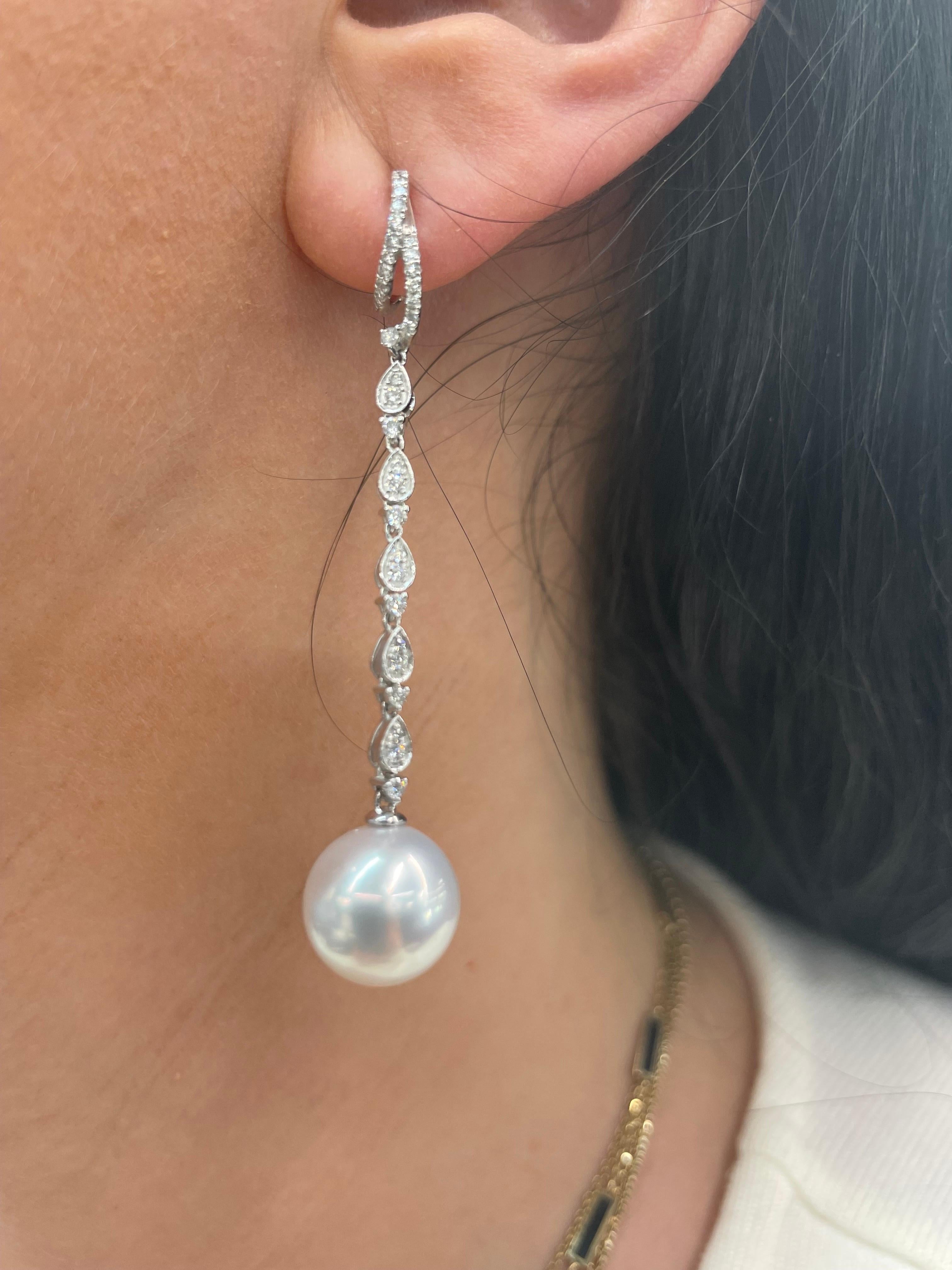 18 Karat White Gold drop earrings featuring two South Sea Pearls measuring 11-12 mm flanked with 68 round brilliants weighing 0.58 carats.
Color G-H
Clarity SI