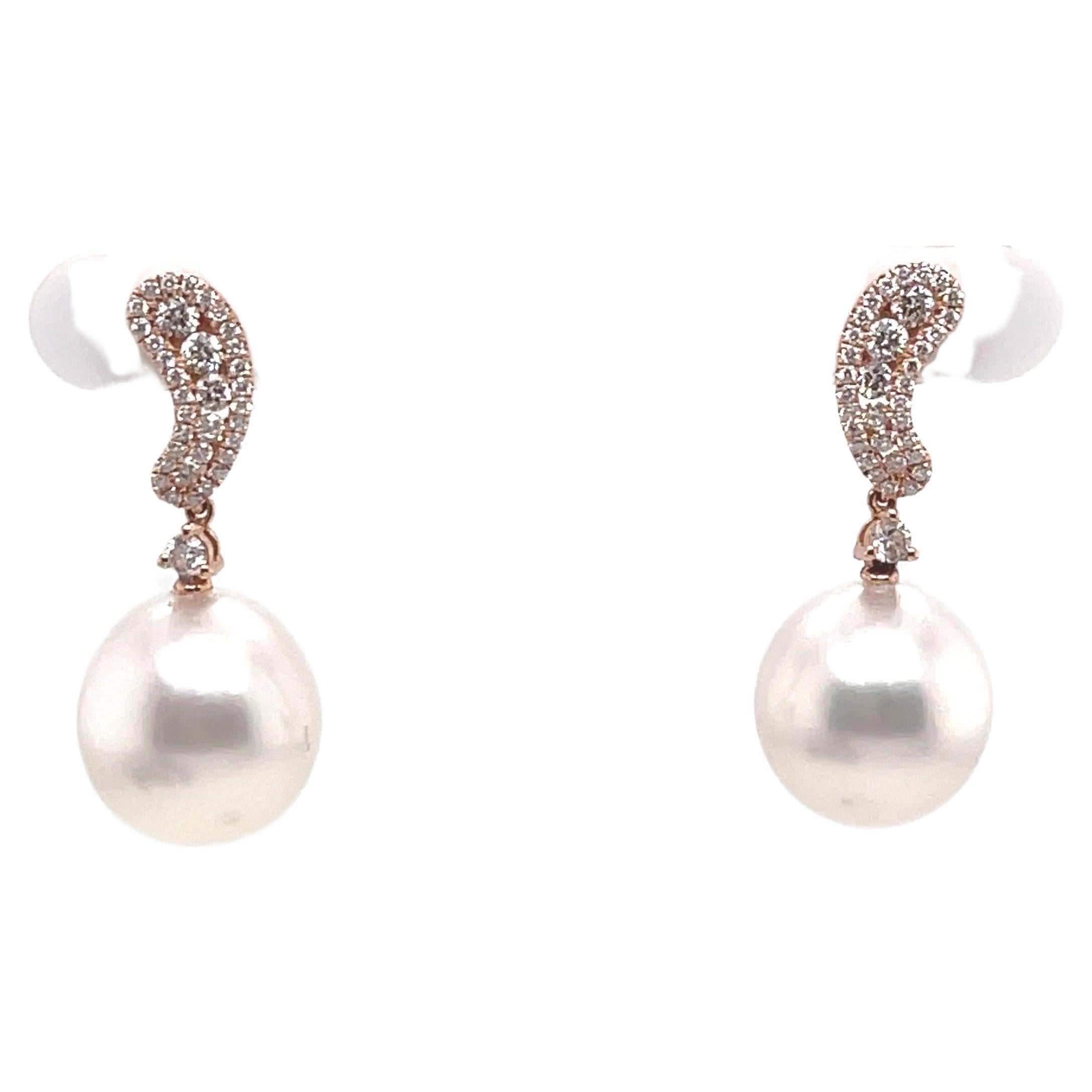 18 Karat rose gold drop earrings featuring two South Sea Pearls measuring 12-13 mm with 8 round brilliants, 0.31 carats and 62 smaller diamonds weighing 0.29 carats. 