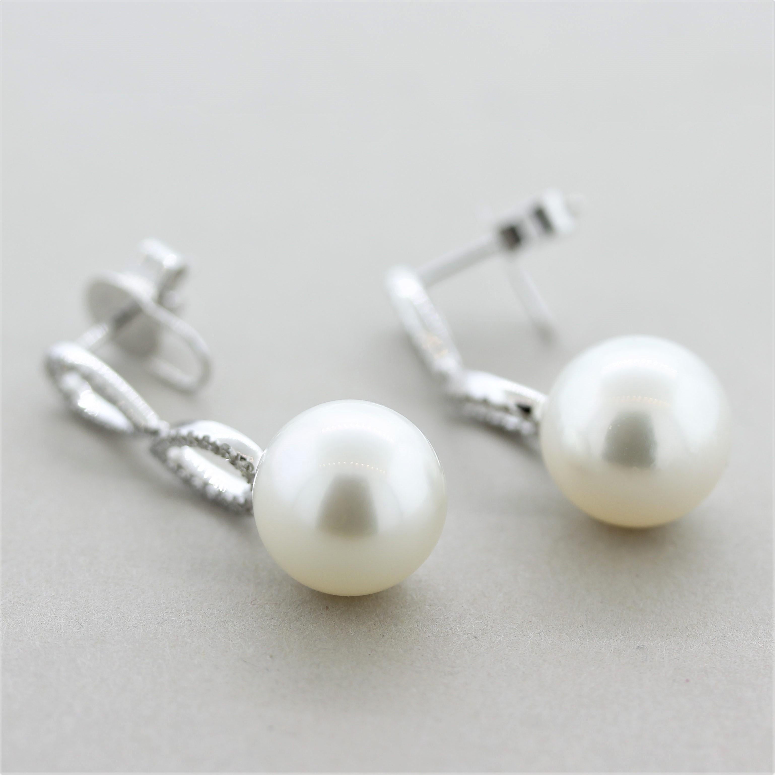 A fine and stylish pair of South Sea pearl drop earrings! The pearls are perfectly matching in shape, color, and size (12mm). They are perfectly round with excellent luster and a soft overtone as they glow in the light. They are accented by 0.44