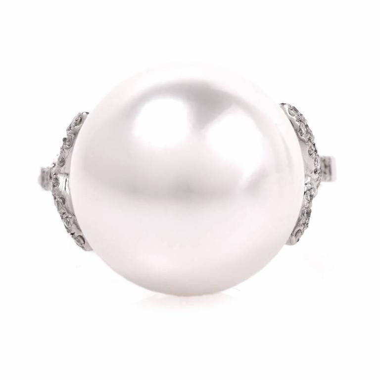 This South Sea pearl and diamond cocktail ring is crafted in solid platinum and weighs 7.4 grams. This classically elegant and timeless cocktail ring exposes a lustrous 12 mm South Sea pearl of ‘white with some pinkish hue’ color. It is flanked by
