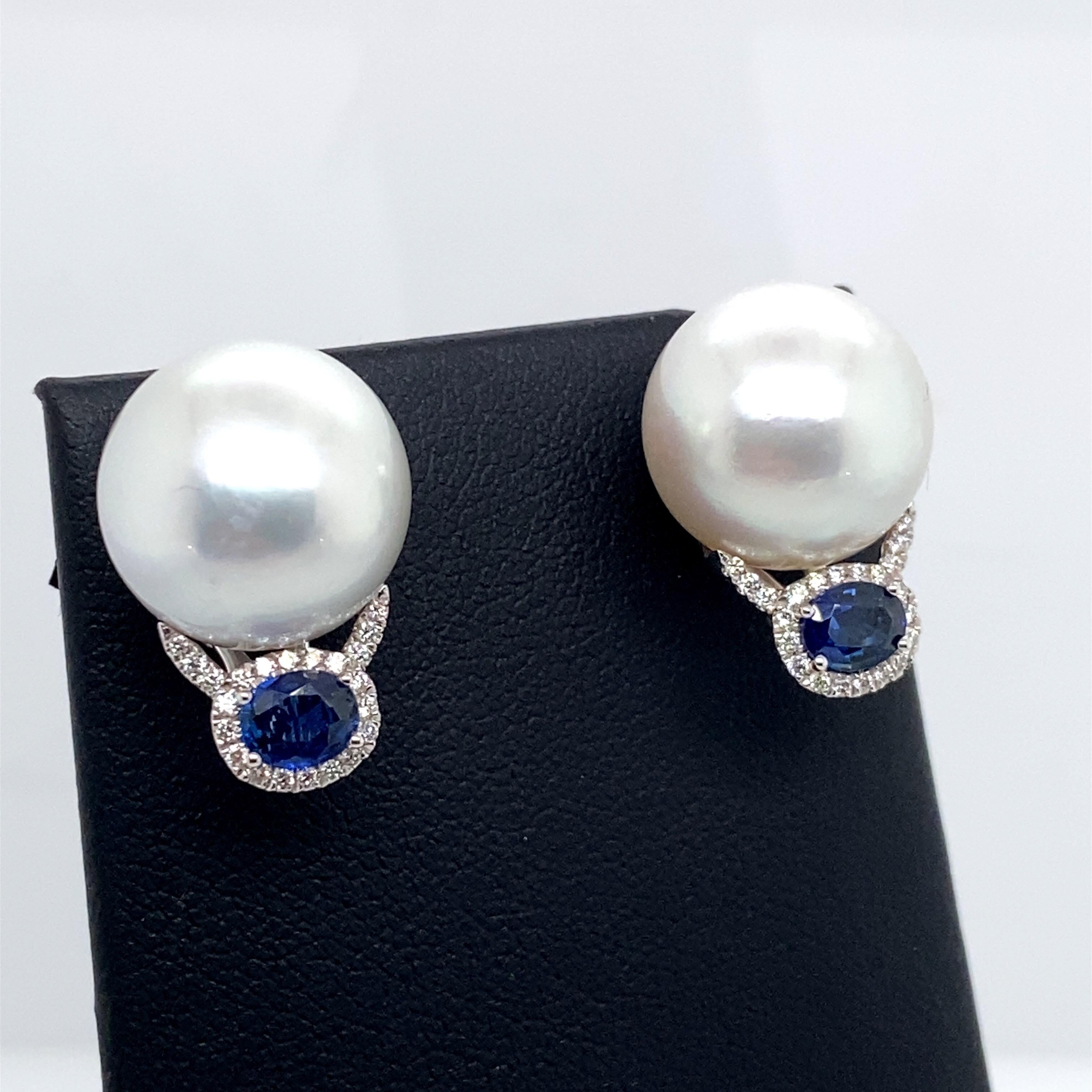 18K White gold drop earrings featuring two South Sea Pearls measuring 13-14 mm with two oval sapphires weighing 0.83 carats surrounded by a diamond halo, 0.16 carats. 
Color G-H
Clarity SI