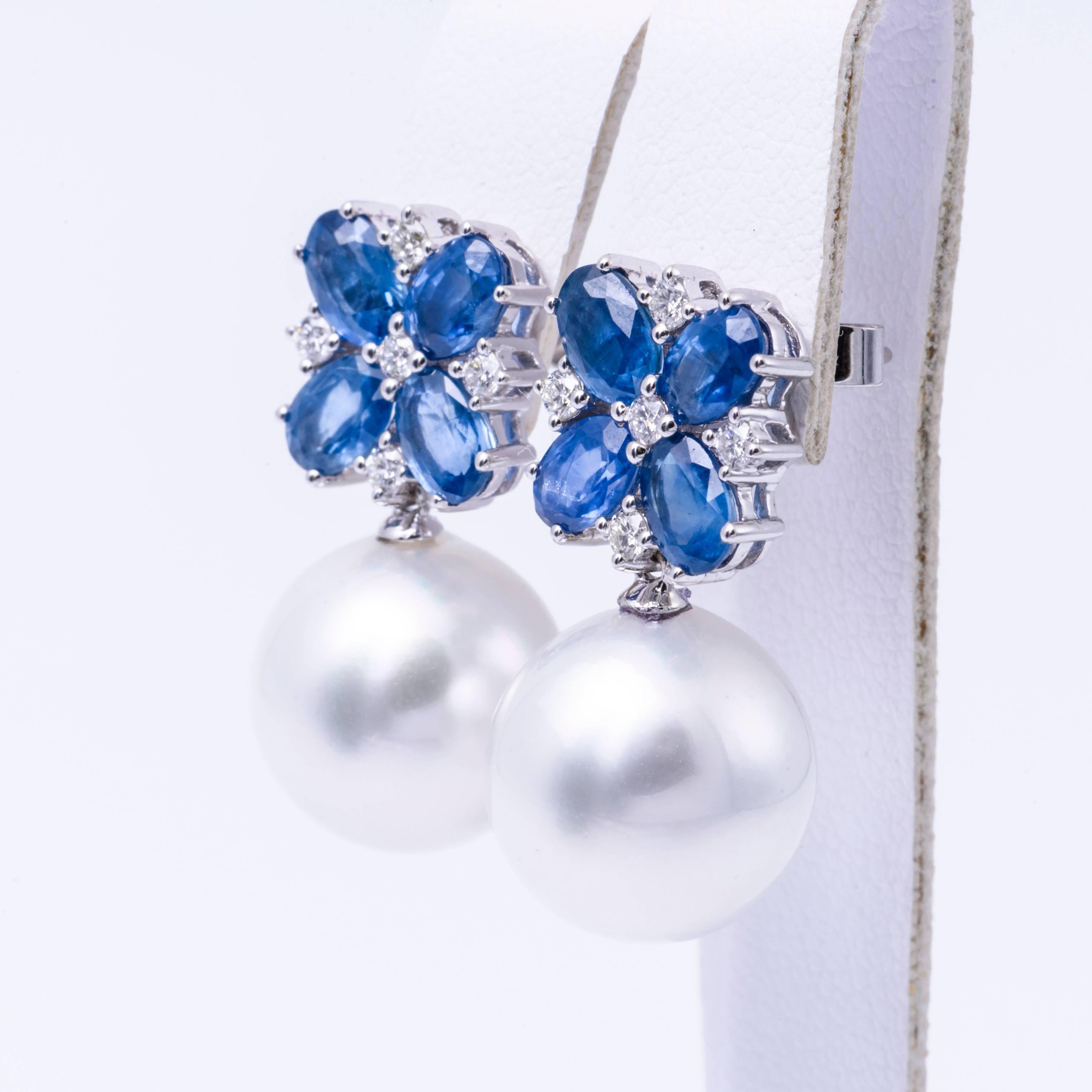 18 Karat White gold drop earrings featuring two South Sea Pearls measuring 13-14 mm with Sapphires, 4.60 carats and diamonds weighing 0.32 carats. 
