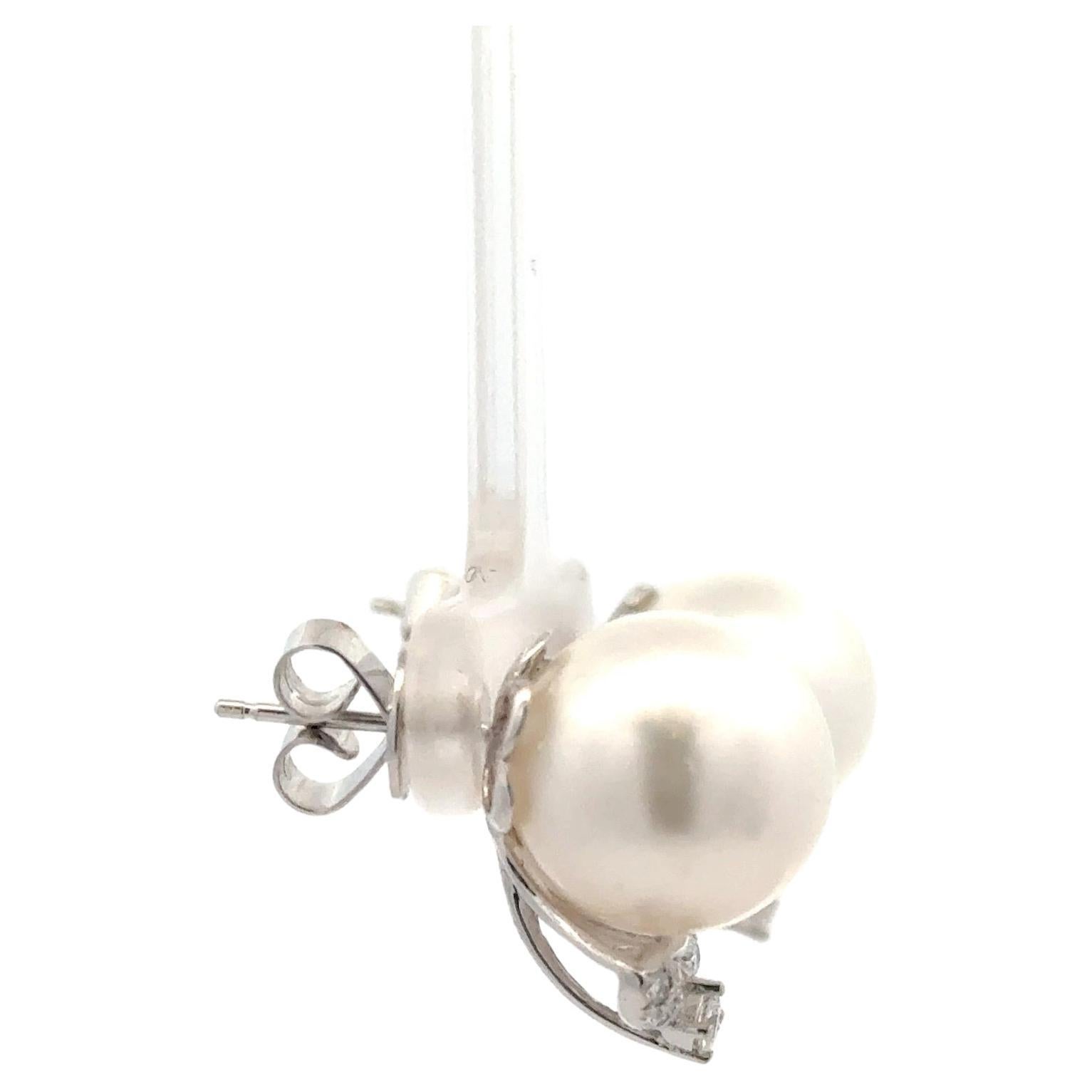 18 Karat white gold stud earrings featuring 2 South Sea Pearls measuring 12-13 MM flanked with 14 round brilliants weighing 0.30 carats.