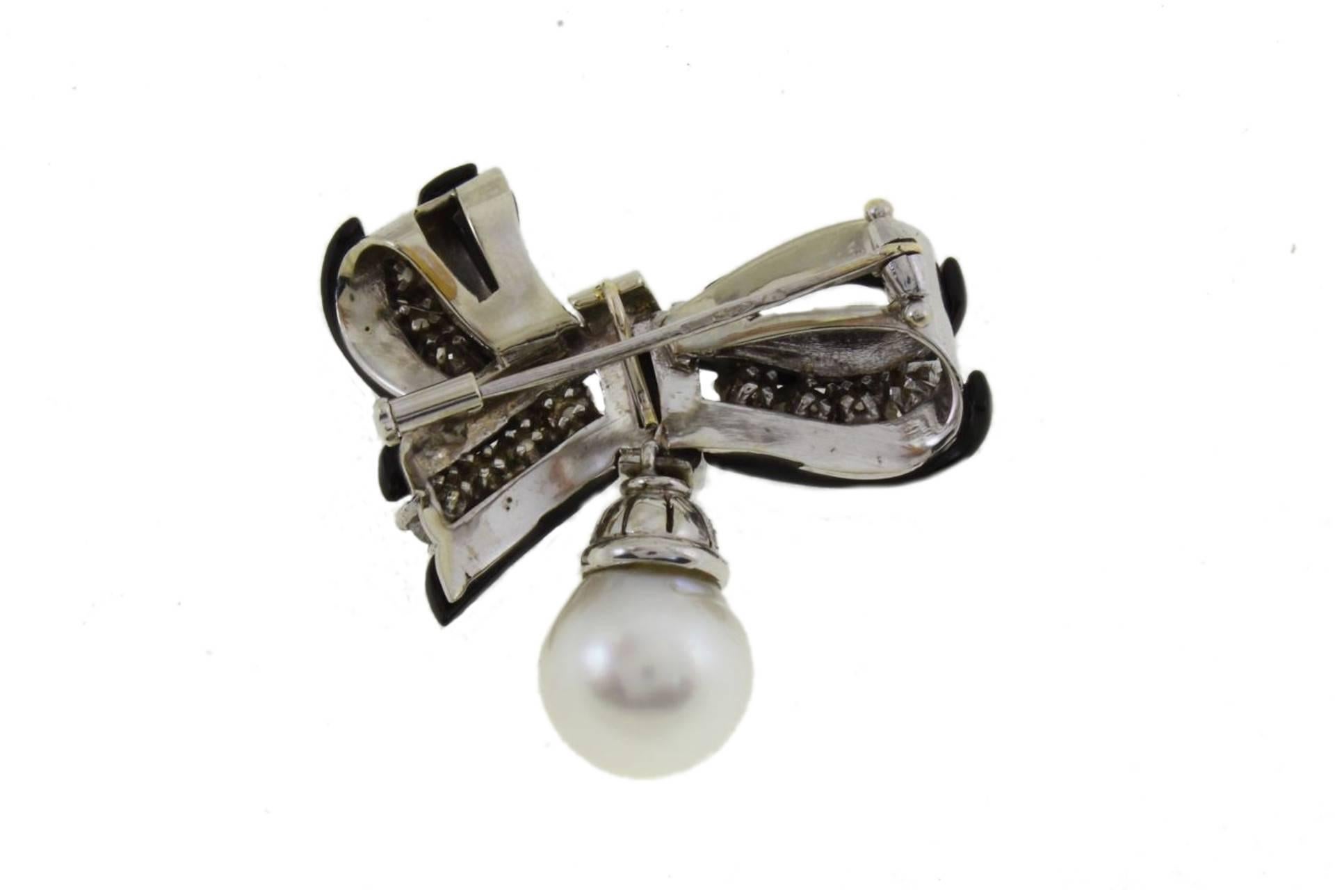 Fashion brooch in 14 kt white gold structure covered by onyx and, between of it, diamonds. As pendant, a structure studded with diamonds and a pearl.
This brooch was totally handmade by Italian master goldsmiths and it is in perfect