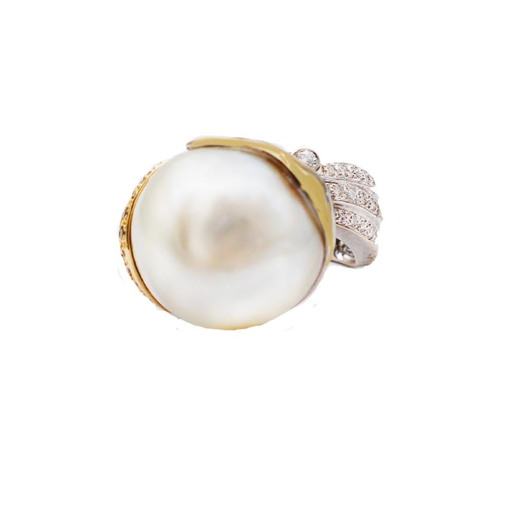 Contemporary, 19.30 mm South Sea Pearl set in a two tones shades of gold: yellow and white set in 18 Karat.
The setting is enhanced with Diamonds & Yellow Sapphires running along side the ring encompassing a beautiful South Sea White colored