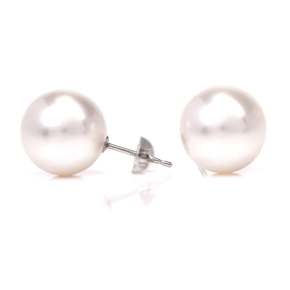 These stud earrings are crafted in 14 karat white gold and weigh 7.4 grams. the expose a pair of lustrous 14mm south sea pearls of  white color and feature posts and clasps designed exclusively for pierced ears. the earrings are in very good
