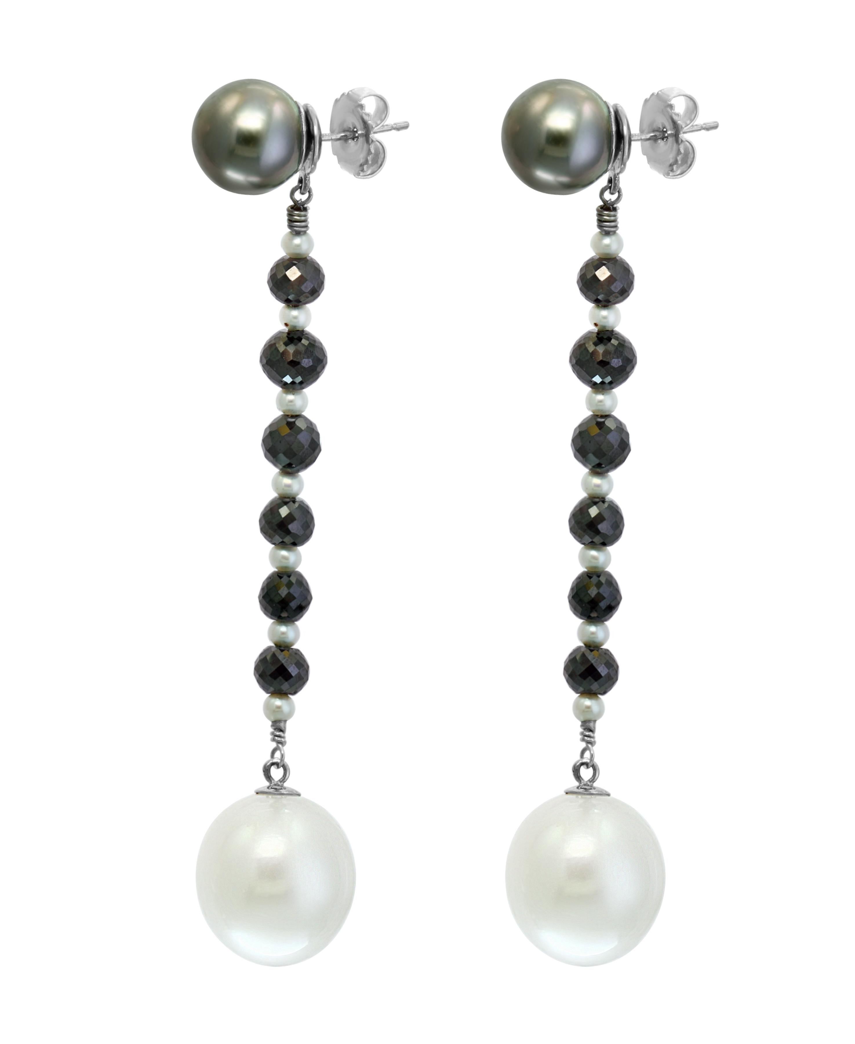 These dangle earrings feature a combination of South Sea Tahitian, cultured round pearls, South Sea white, drop shape cultured pearls, and black diamonds. The Tahitian pearls rest on the ear while the South Sea drops dangle from alternating small