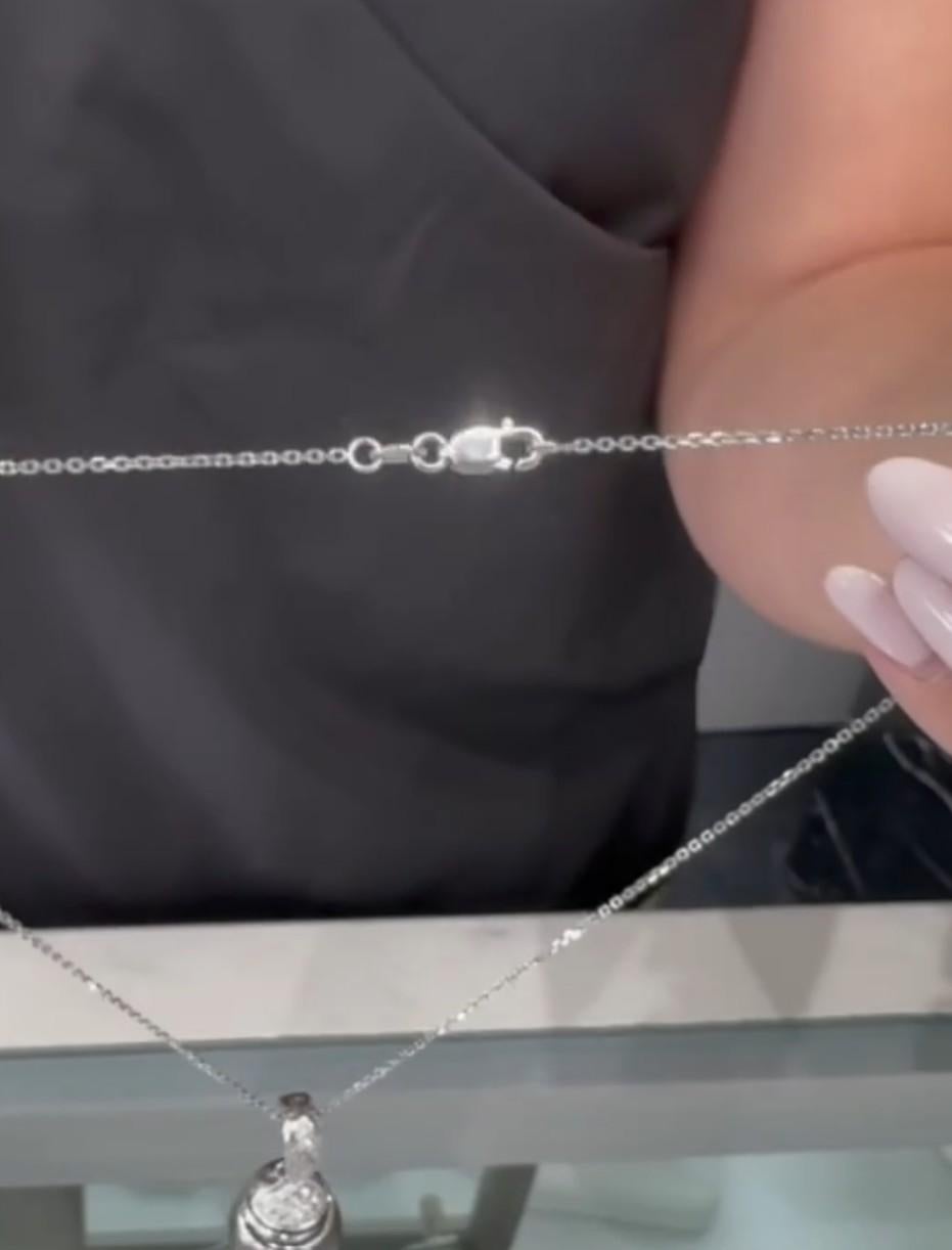 Pendente in oro bianco 18 carati con diamanti rotondi sfaccettati del peso totale di 0,30 carati e una perla nera di Tahiti di 14,99 mm.  Il ciondolo è dotato di una chiusura che permette di agganciare e sganciare la collana.

- Il ciondolo scorre