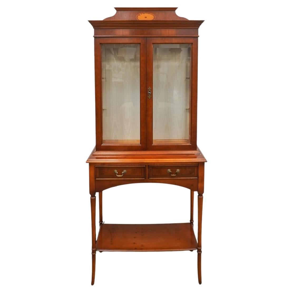 Good quality yew display cabinet on stand by Bradley. 
 Coming in two main sections for ease of movement. Upper cabinet section with twin opening glazed doors with locking key, revealing removable glass shelving. 
 Lower stand section with twin