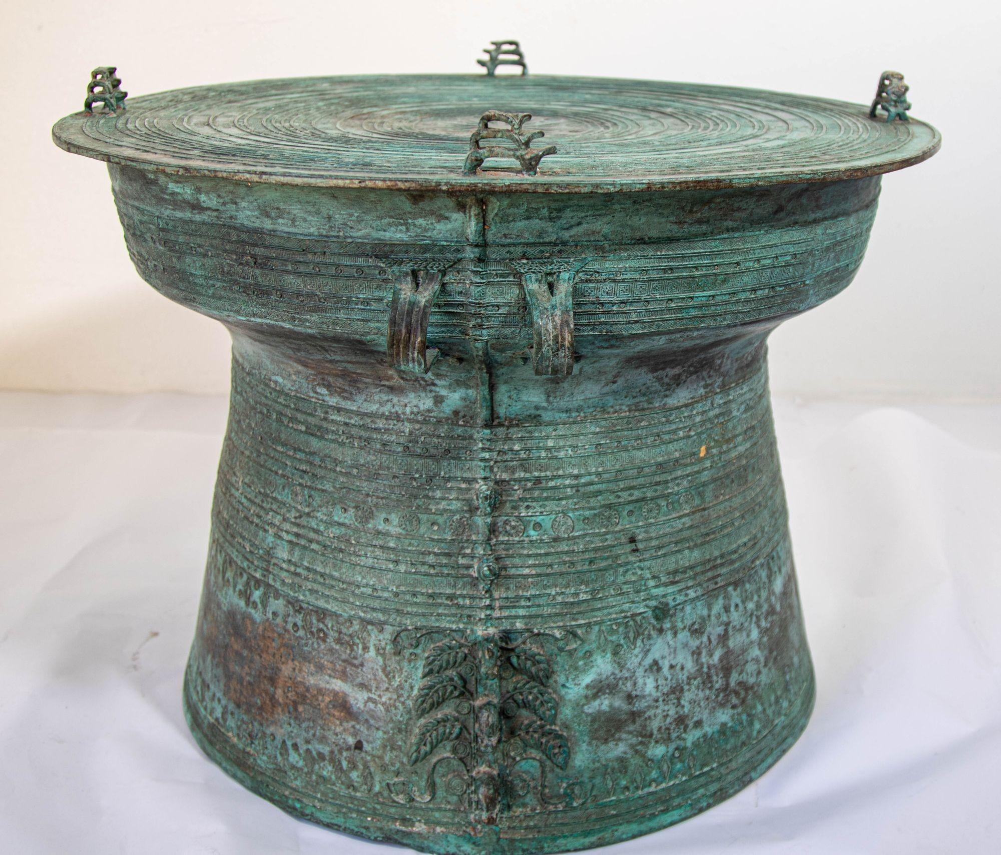 Large Southeast Burmese Bronze Asian Rain Drum Side Table: This impressive 22-inch diameter Asian cast bronze rain drum features intricate detailing with traditional geometric relief motifs.
The body and top display precise patterns, including