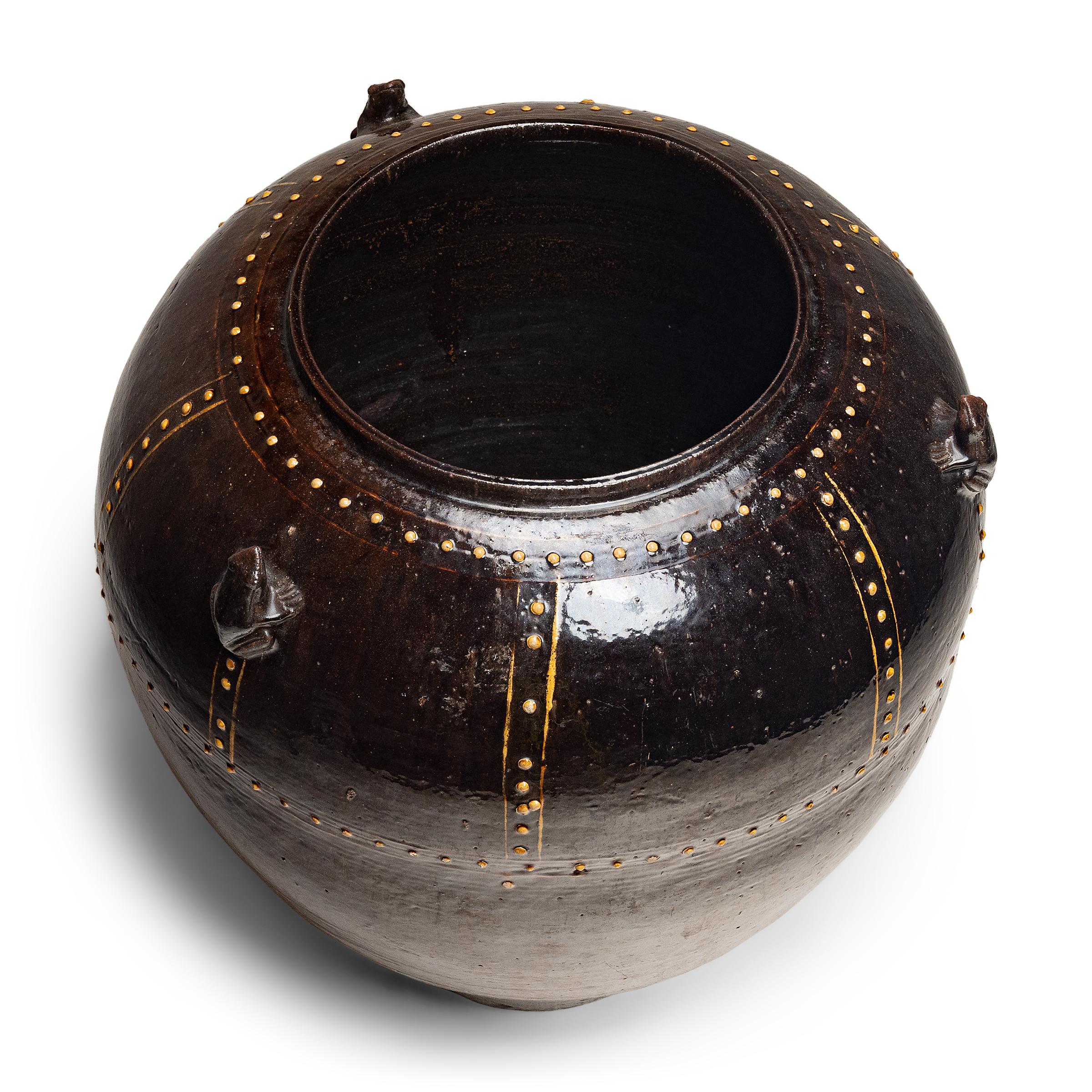 Dieses große Steingutgefäß aus Myanmar oder Thailand aus dem 19. Jahrhundert ist mit dunkelbrauner Glasur übergossen und mit einem Knopfmuster aus erhabenen Linien und Punkten verziert. Diese Art von ungeschliffenen, eiförmigen Gefäßen, die aufgrund