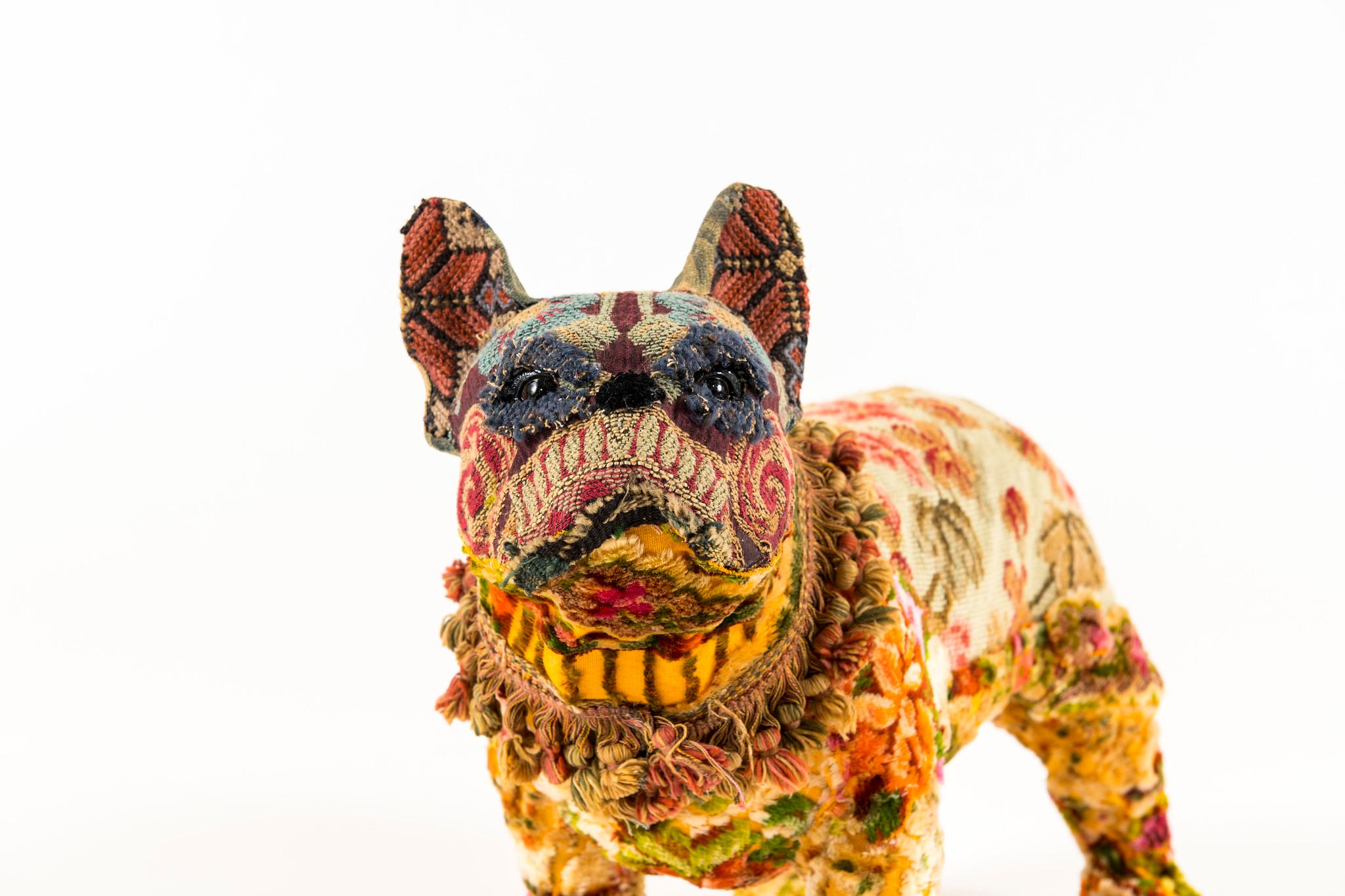 Maxie is flower embellished bull dog with a mix of bright textiles to include: 1940s floral needlepoint body; vintage cut chenille on underbody neck, and legs; vintage embroidery from costume on Maxie's face; antique fringe trim collar and face