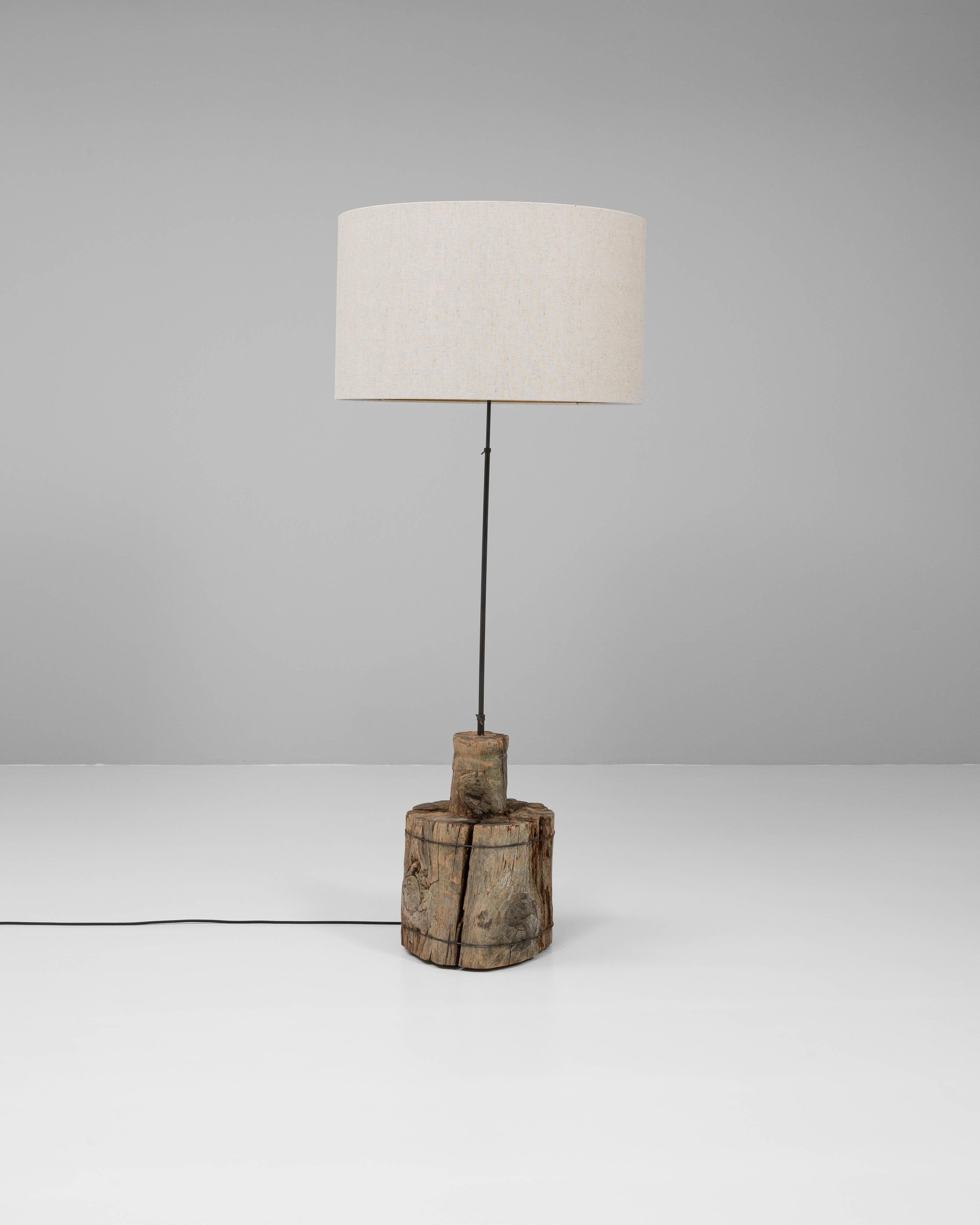 Ce lampadaire du sud de l'Europe est une fusion frappante d'éléments de design organiques et industriels. Sa base sculpturale est fabriquée à partir d'un segment massif de bois vieilli, richement texturé avec des fissures visibles, des veines et une