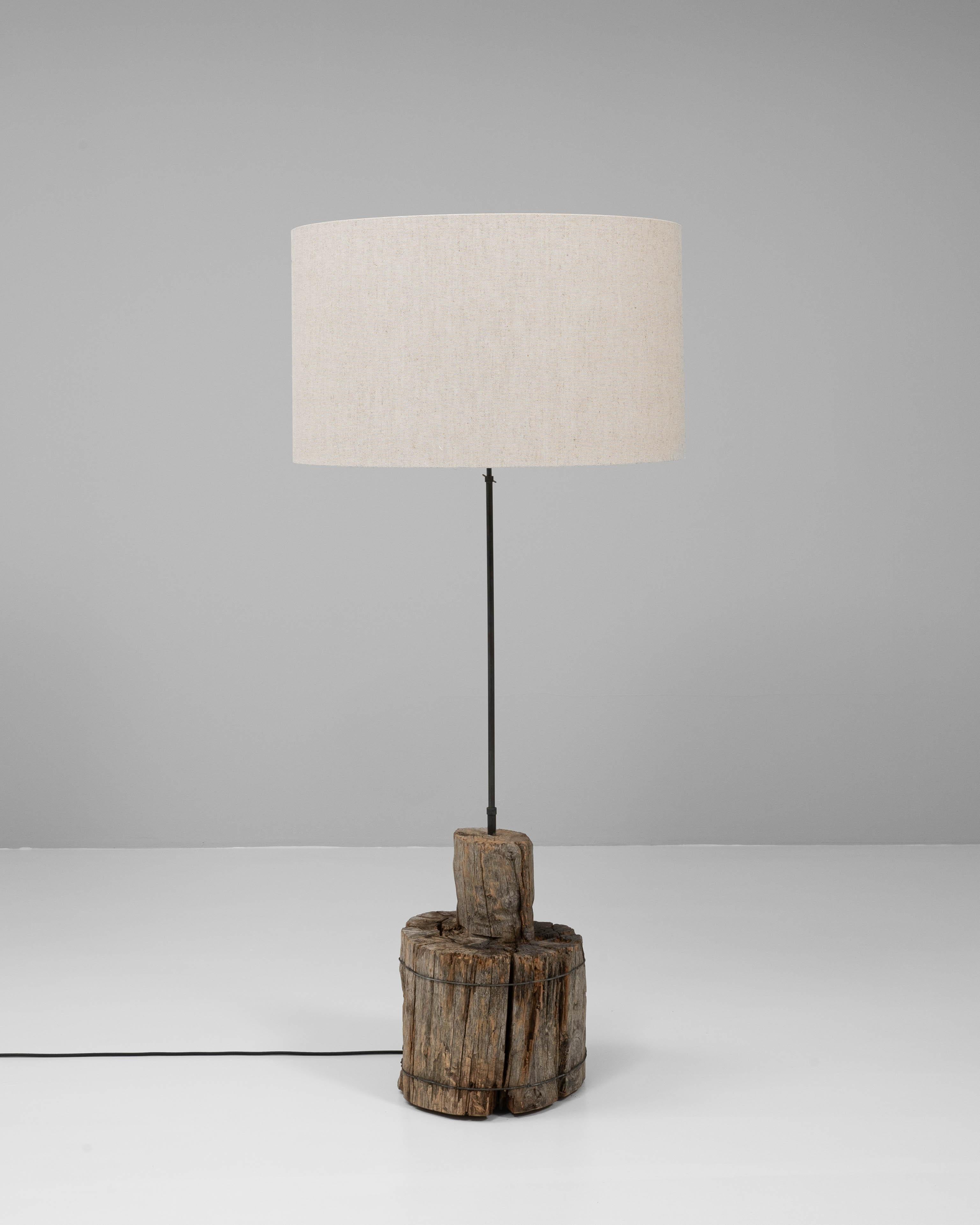 Ce lampadaire du sud de l'Europe est une fusion frappante d'éléments de design organiques et industriels. Sa base sculpturale est fabriquée à partir d'un segment massif de bois vieilli, richement texturé avec des fissures visibles, des veines et une