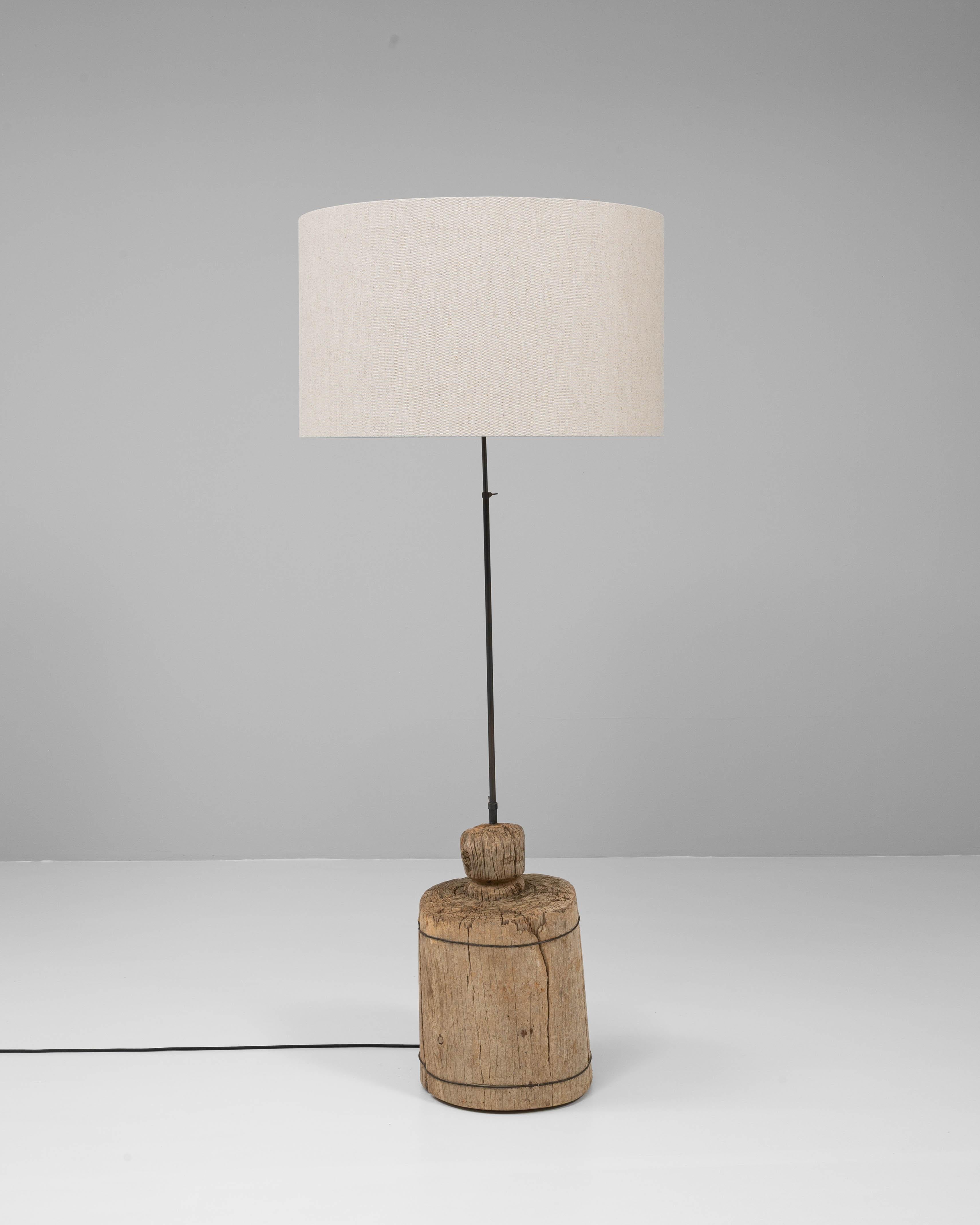 Ce lampadaire du sud de l'Europe est une fusion frappante d'éléments de design organiques et industriels. Sa base sculpturale est fabriquée à partir d'un segment massif de bois vieilli, richement texturé avec des fissures visibles, des veines et une