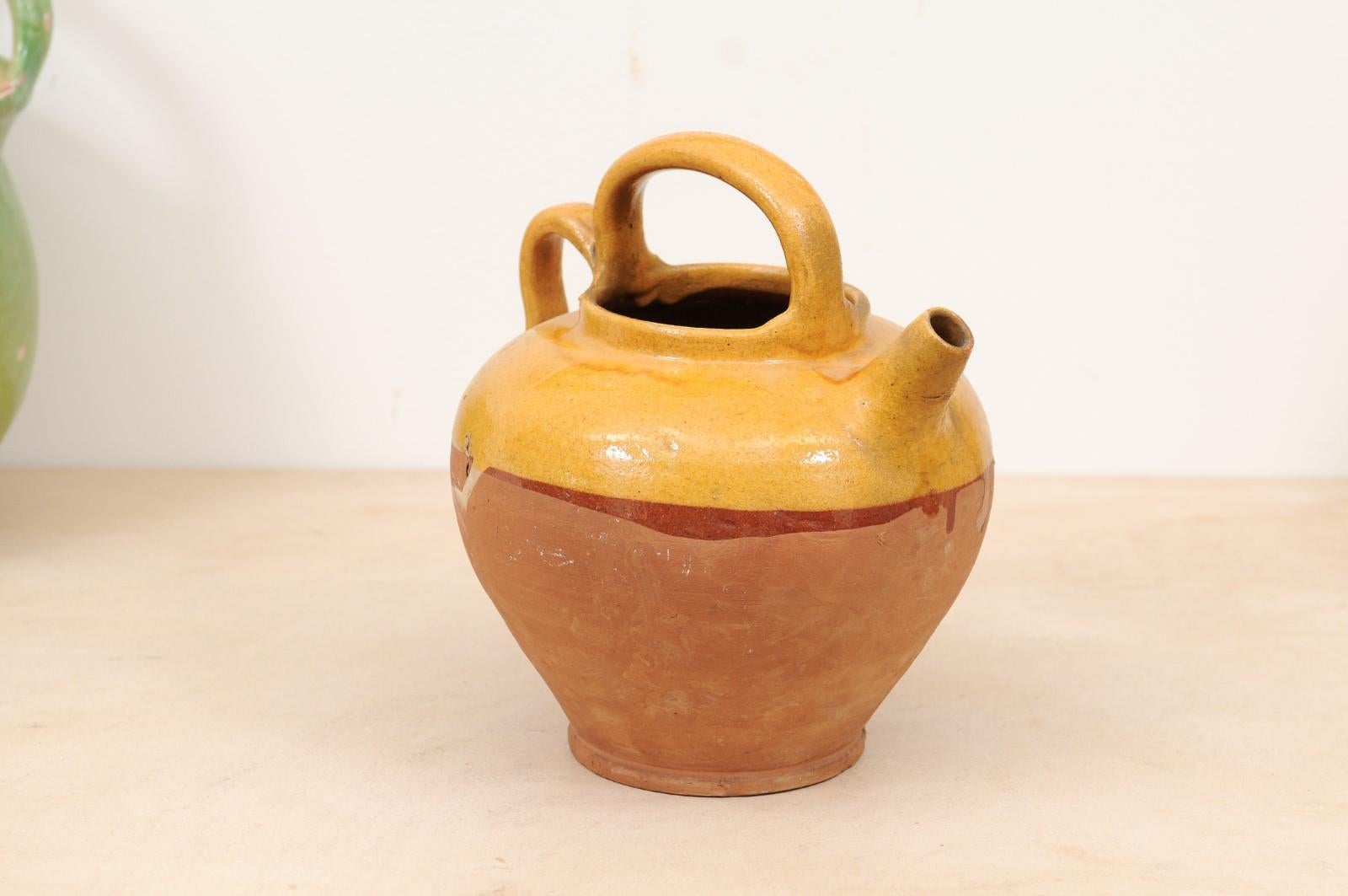 A Southern French olive oil pot from the 19th century, with yellow glazed décor and two handles. Created in Southern France during the 19th century, this Provençal olive oil pot features a circular tapering body adorned with yellow glaze in its