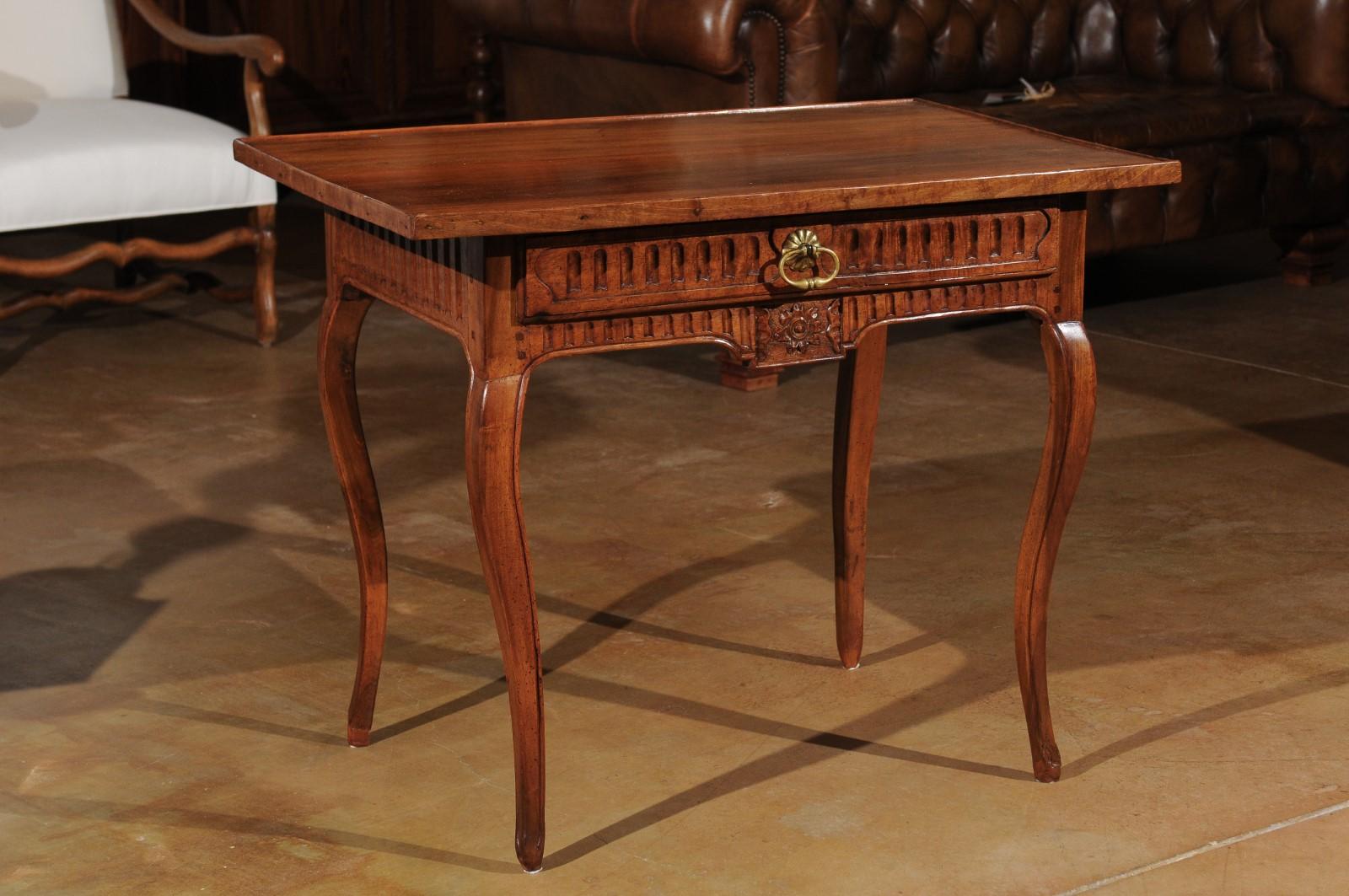 A southern French transitional walnut side table from the third quarter of the 18th century, with carved apron and cabriole legs. Born at the end of the reign of King Louis XV at a time when the Rococo style was transitioning to calmer, more classic
