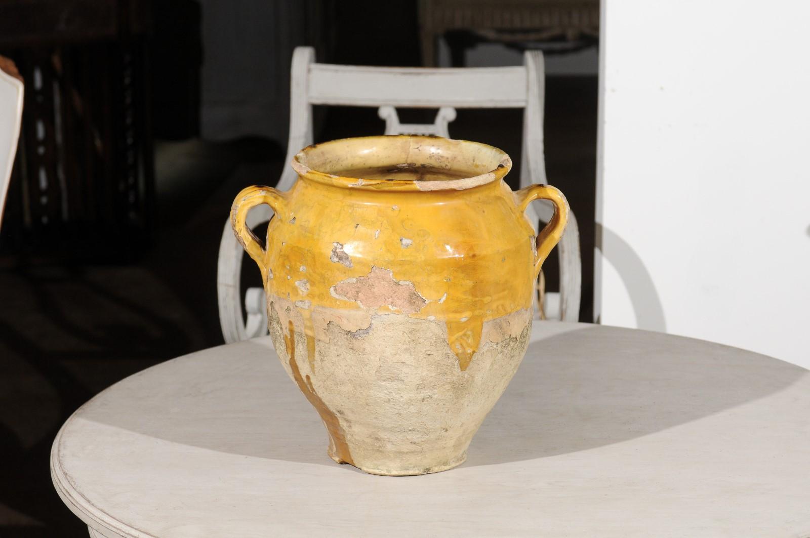 A French yellow glazed terracotta confit pot from the mid-19th century with two handles. Born in France in the early years of Napoleon III's reign, this confit pot features a typical yellow glaze in its upper section that drips delicately down to