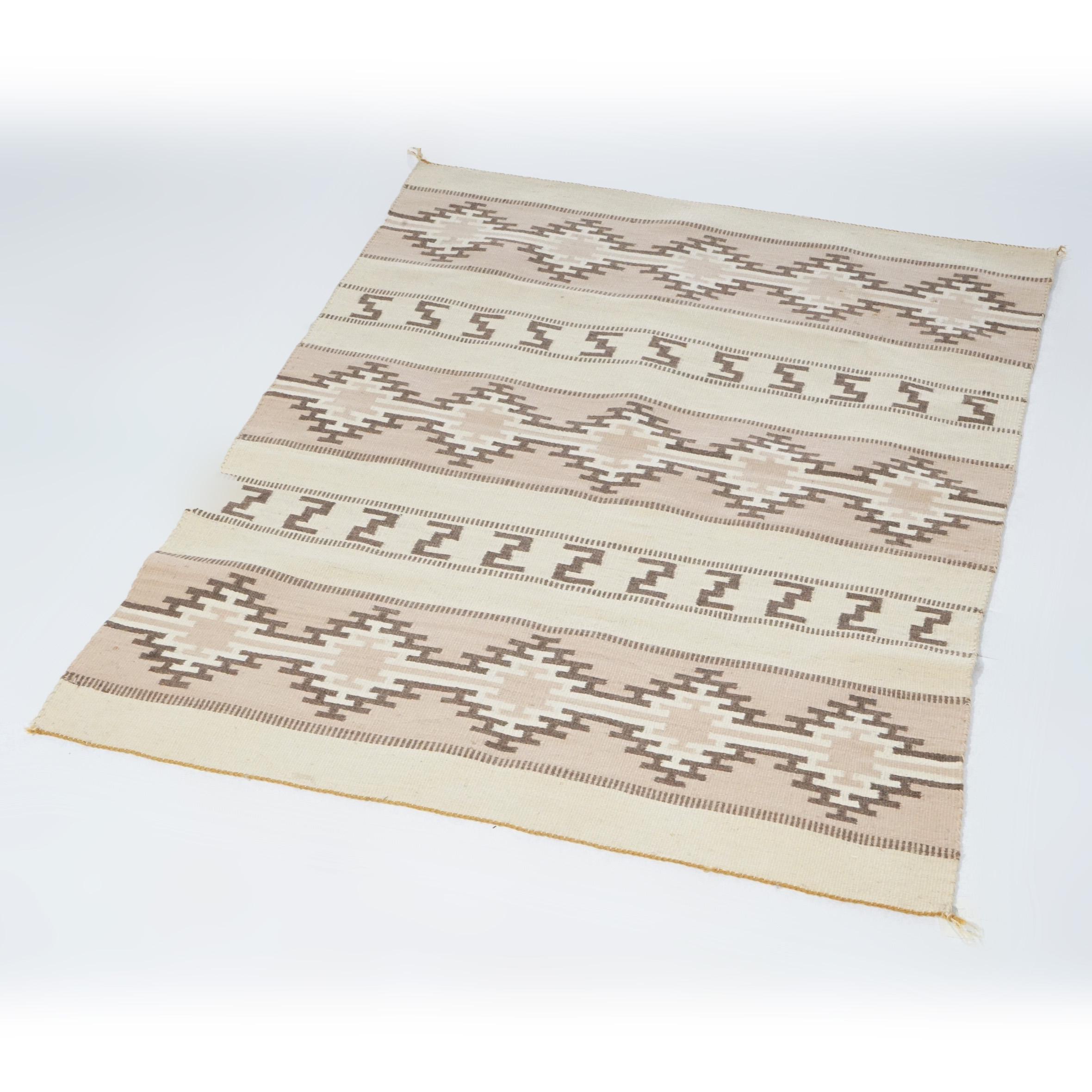 A southwestern American Indian Navajo style rug offers wool construction with stripes having repeating geometric design, 20th Century. 

Measures - 45 1/2