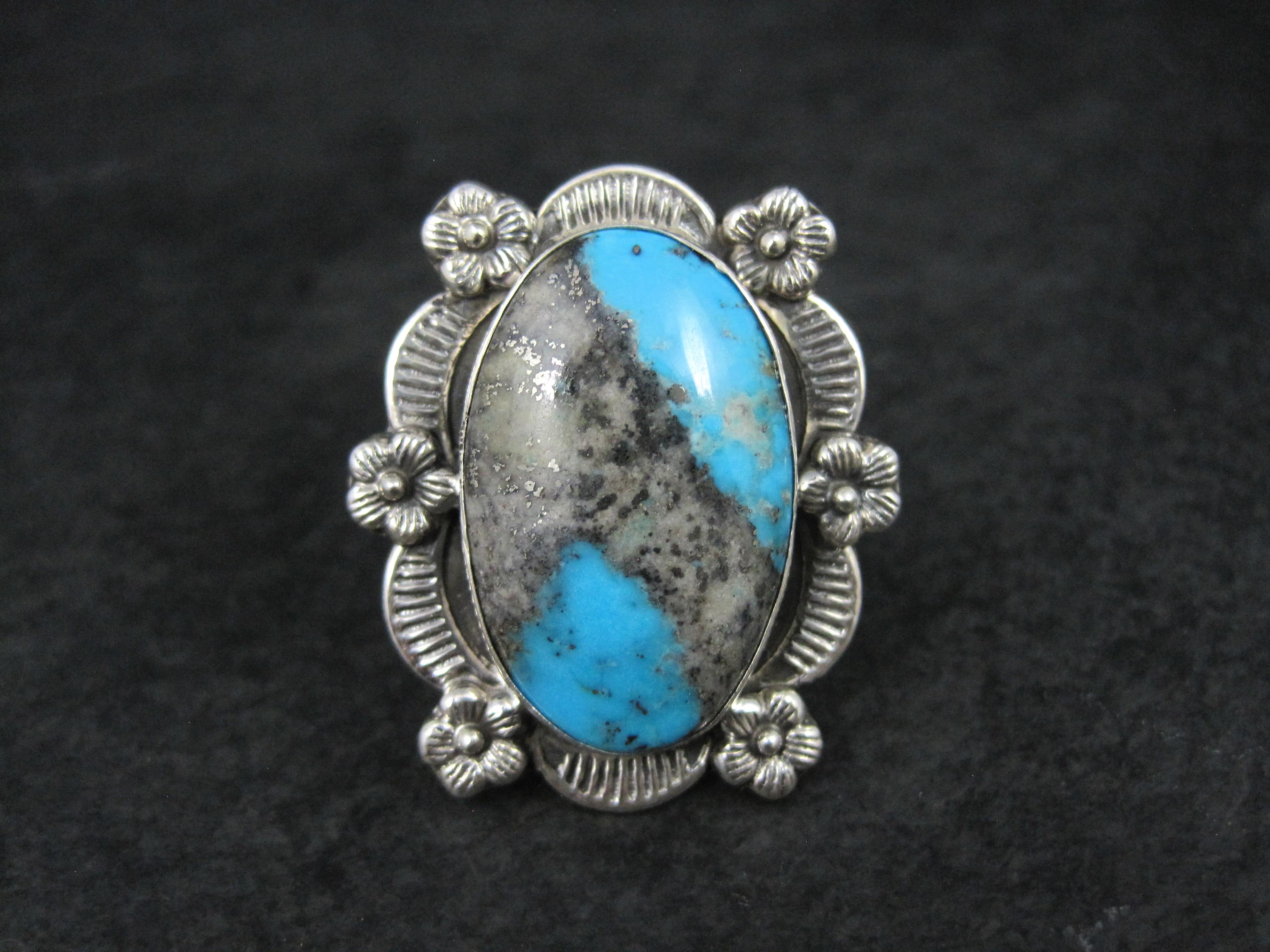 This beautiful Southwestern style ring is sterling silver. 
It features a beautiful floral design and a stunning 16x25mm boulder turquoise gemstone.
The face of this ring measures 1 1/8 inches east to west and 1 5/16 inches north to south.
Size: