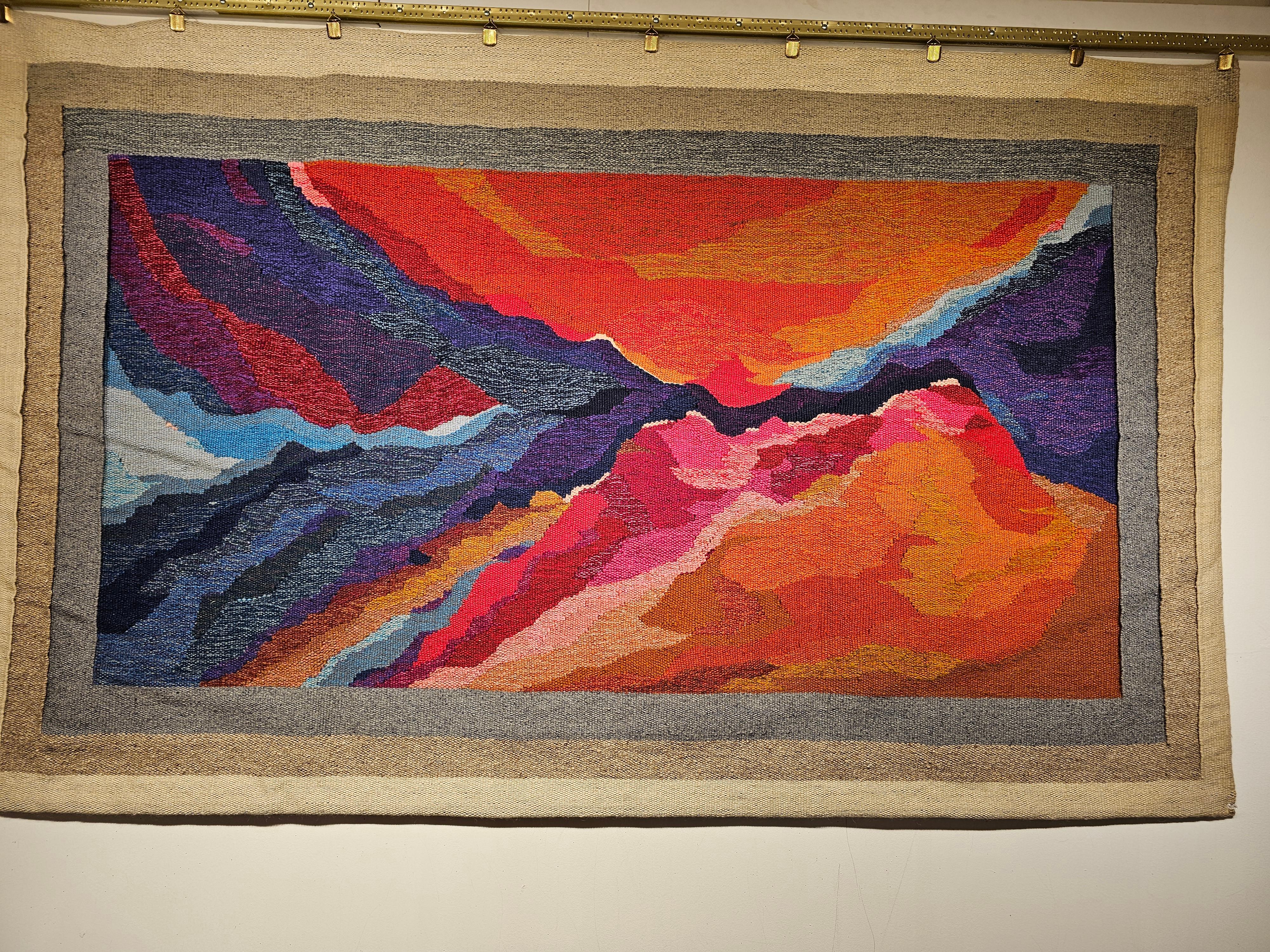 Beautiful and colorful mid century modern hand woven tapestry with an abstract depiction capturing the light and colors in the American Southwest landscape of mountains and canyons at the sunrise or sunset. The tapestry is very much in the style of
