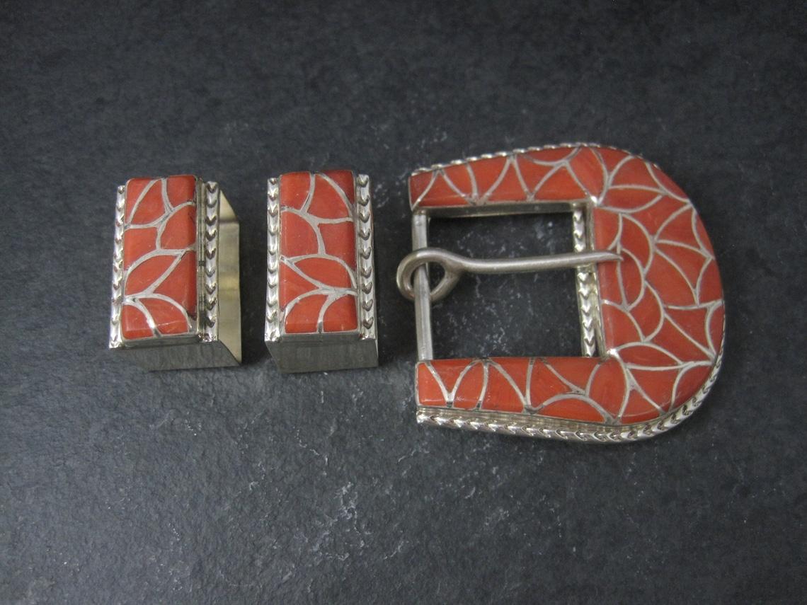 This beautiful belt buckle set is sterling silver with coral inlay.

The slides measures 5/8 by 1 1/16 inches - the buckle measures 2 1/16 by 2 1/16 inches.
This buckle set is made to fit a 1 inch belt.

Marks: None

Condition: New Old Stock / Never