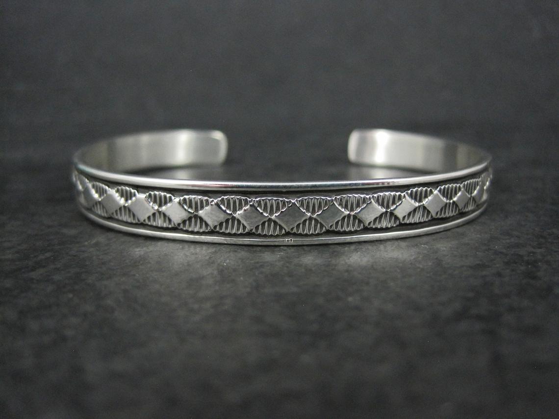 This beautiful Southwestern cuff bracelet is sterling silver.
It is a creation of Navajo silversmith Bruce Morgan.

Measurements: 1/4 of an inch wide - Inner circumference of 6 inches including the 1 inch gap.

Marks: B Morgan, Sterling

Condition:
